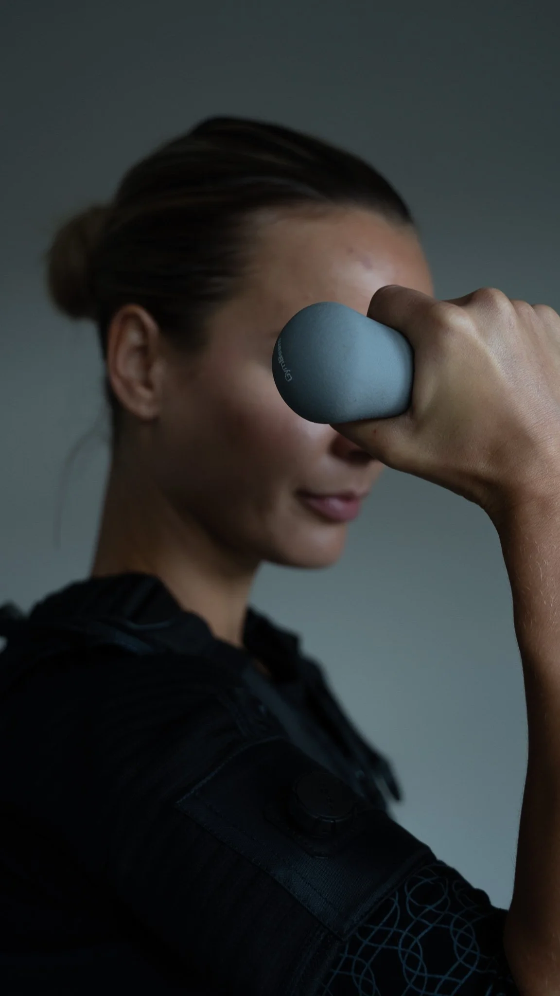 Kvinde der træner med håndvægte, bruger en grå håndvægt i venstre hånd, og har fokus på sit træningspas.