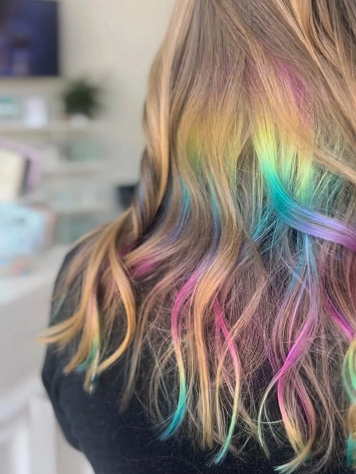 back of woman's blonde hair with peekaboo rainbow highlights