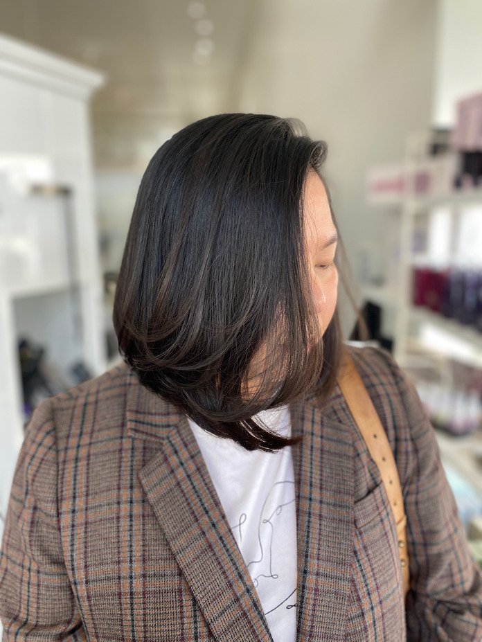 woman uses new hair cut of short brown bob to cover her face