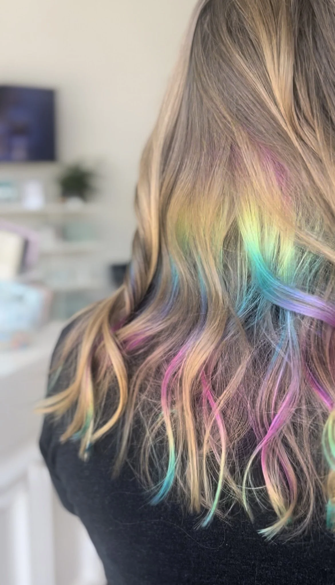 back of woman's blonde hair with peekaboo rainbow highlights