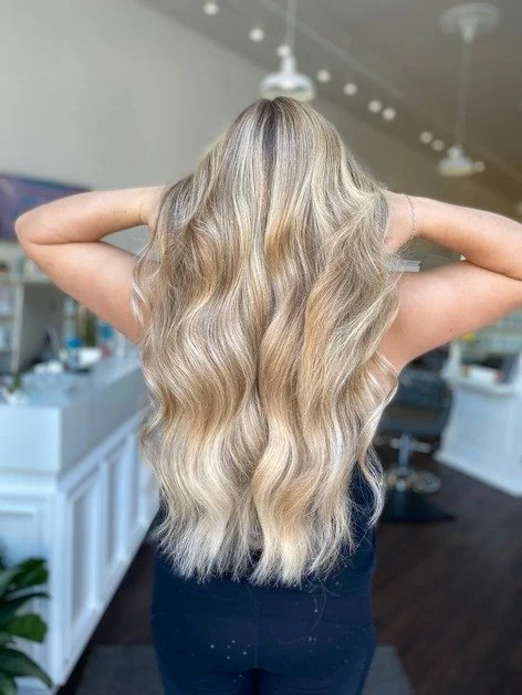 girl fans out freshly blonded long wavy hair 