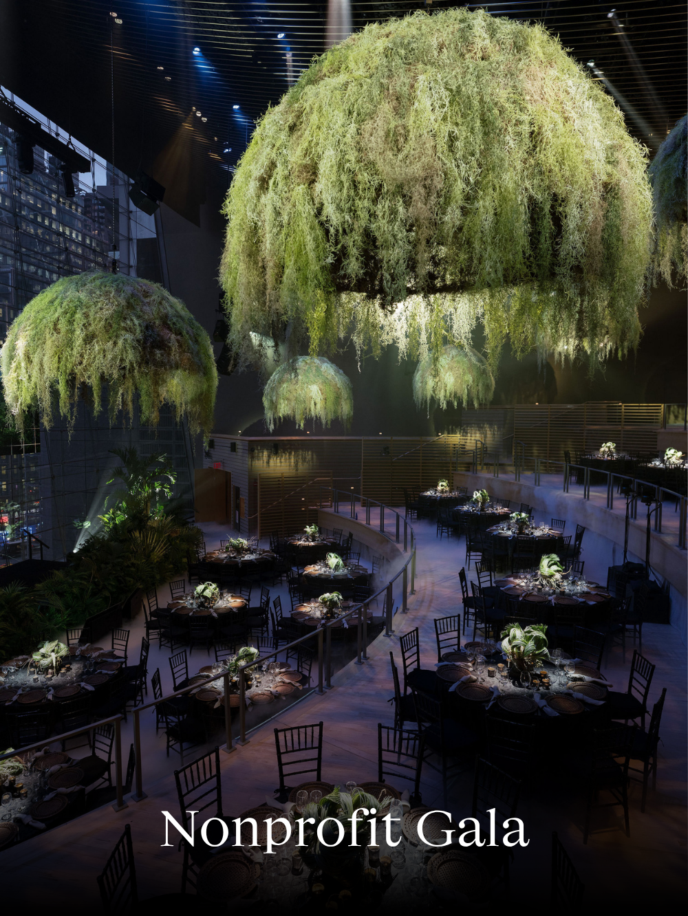 Nonprofit gala event with suspended botanical installations and dramatic lighting design