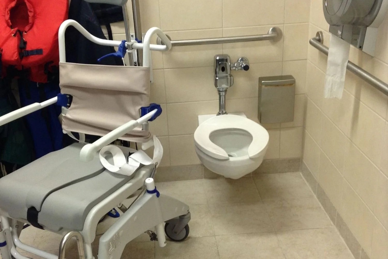 Salle de bain adaptée dans un centre communautaire avec une chaise d'aisance.