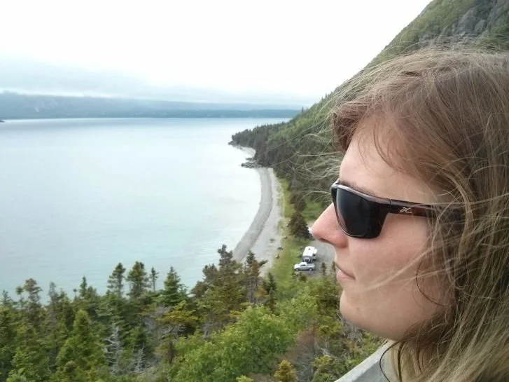 Visage de Stéphanie devant un paysage en flanc de montagne, près de l'eau