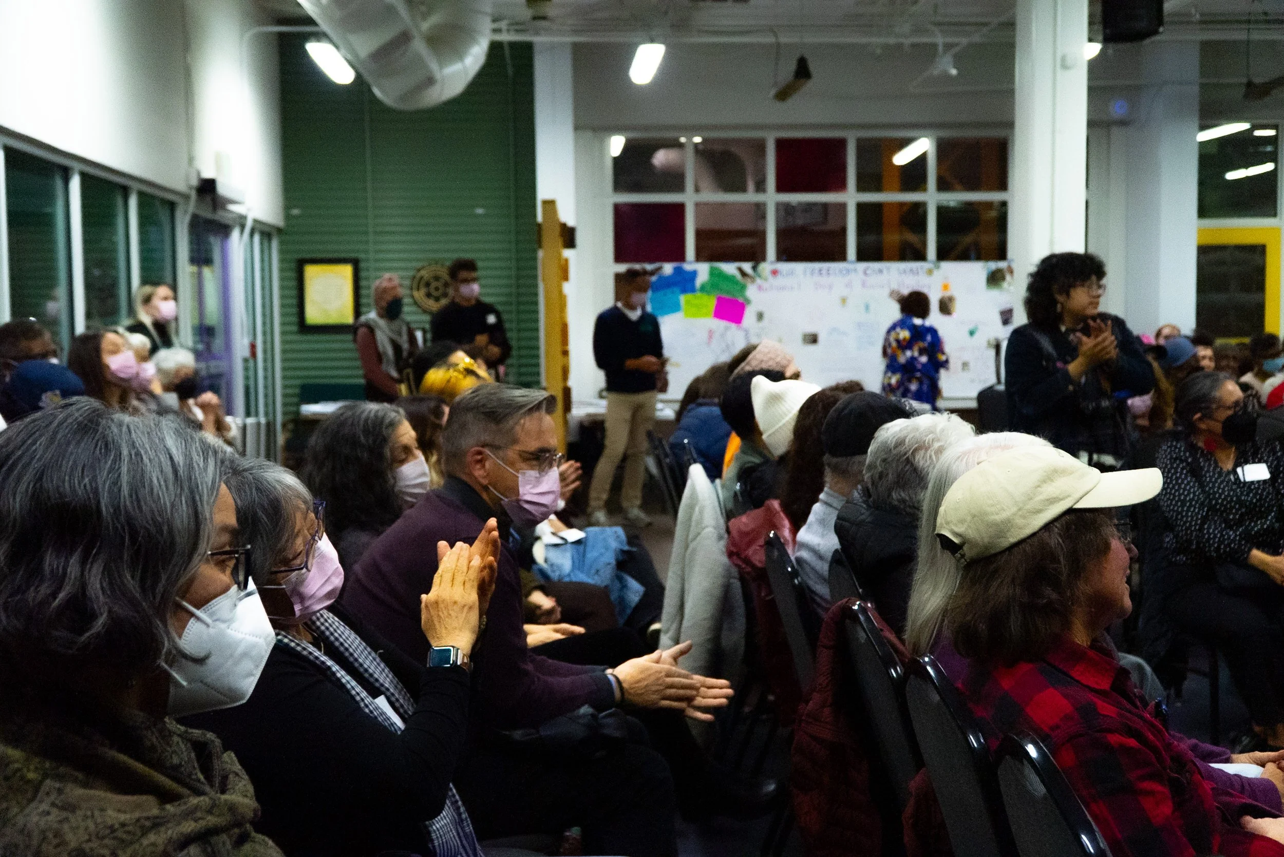 An audience of diverse folks watches and applauds.