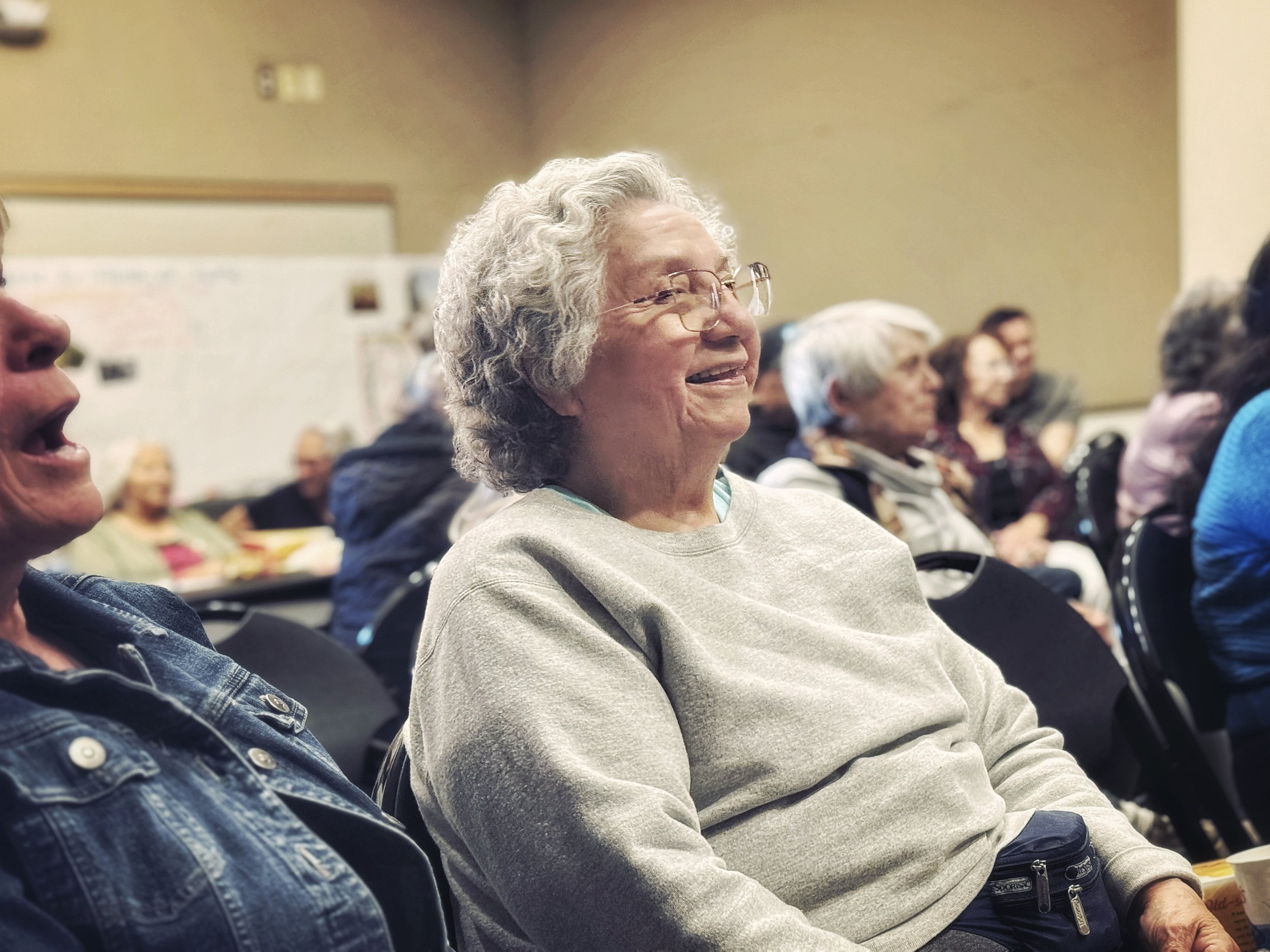 A woman sits in the audience, smiling, enjoying the show