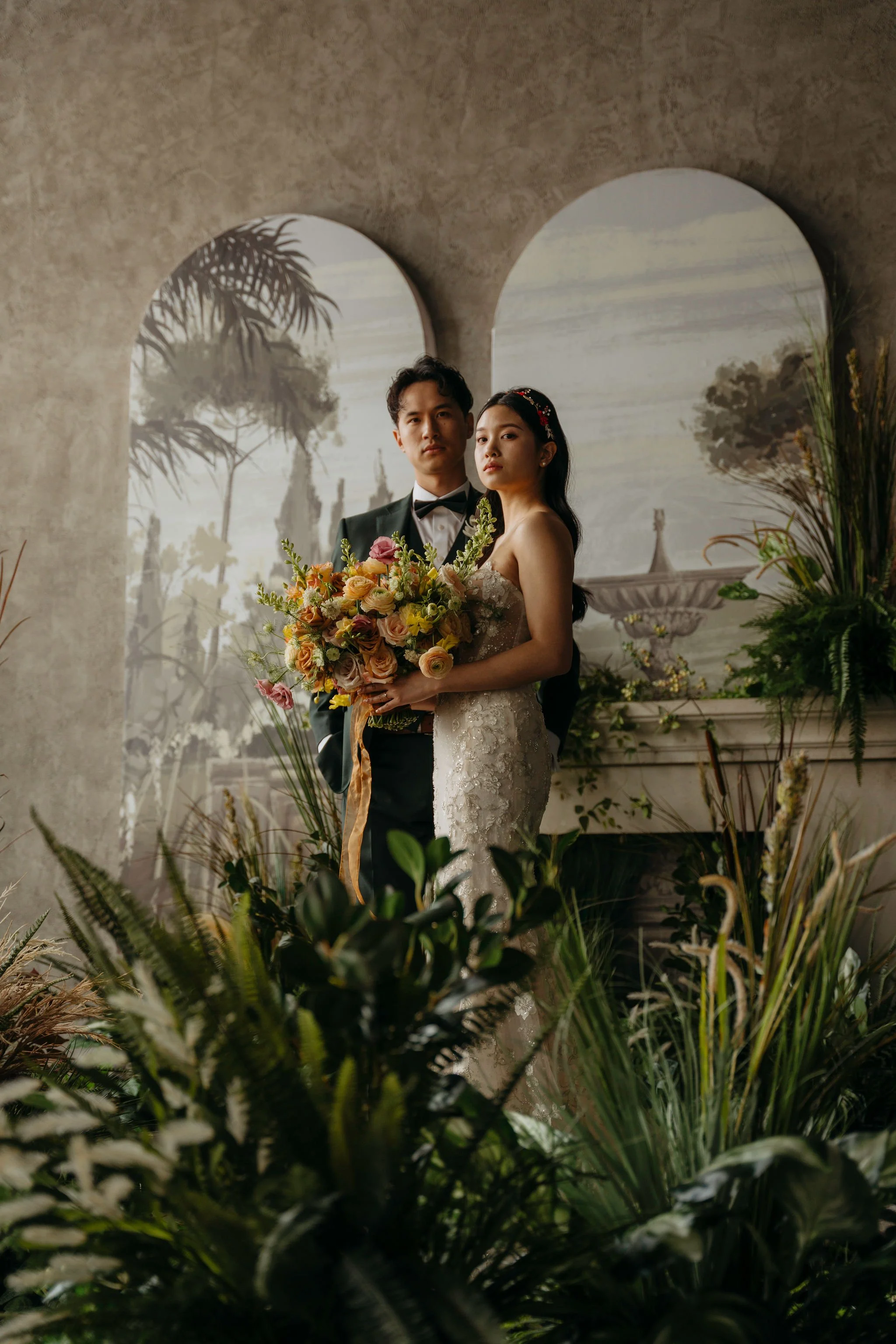 Moody edit of Bride and Groom posing in studio with florals