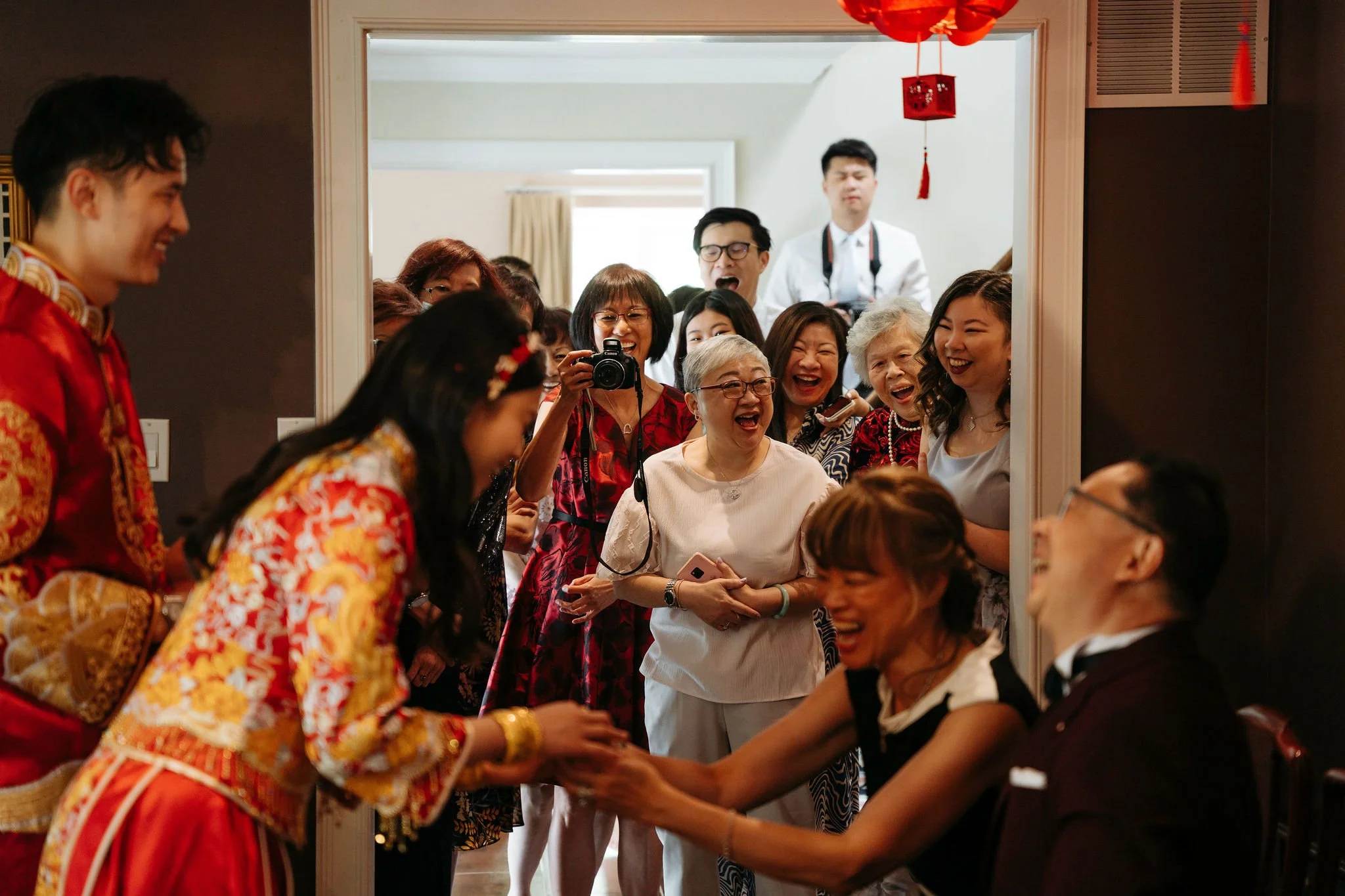 Bride and Groom participating in a tea ceremony with family smiling behind