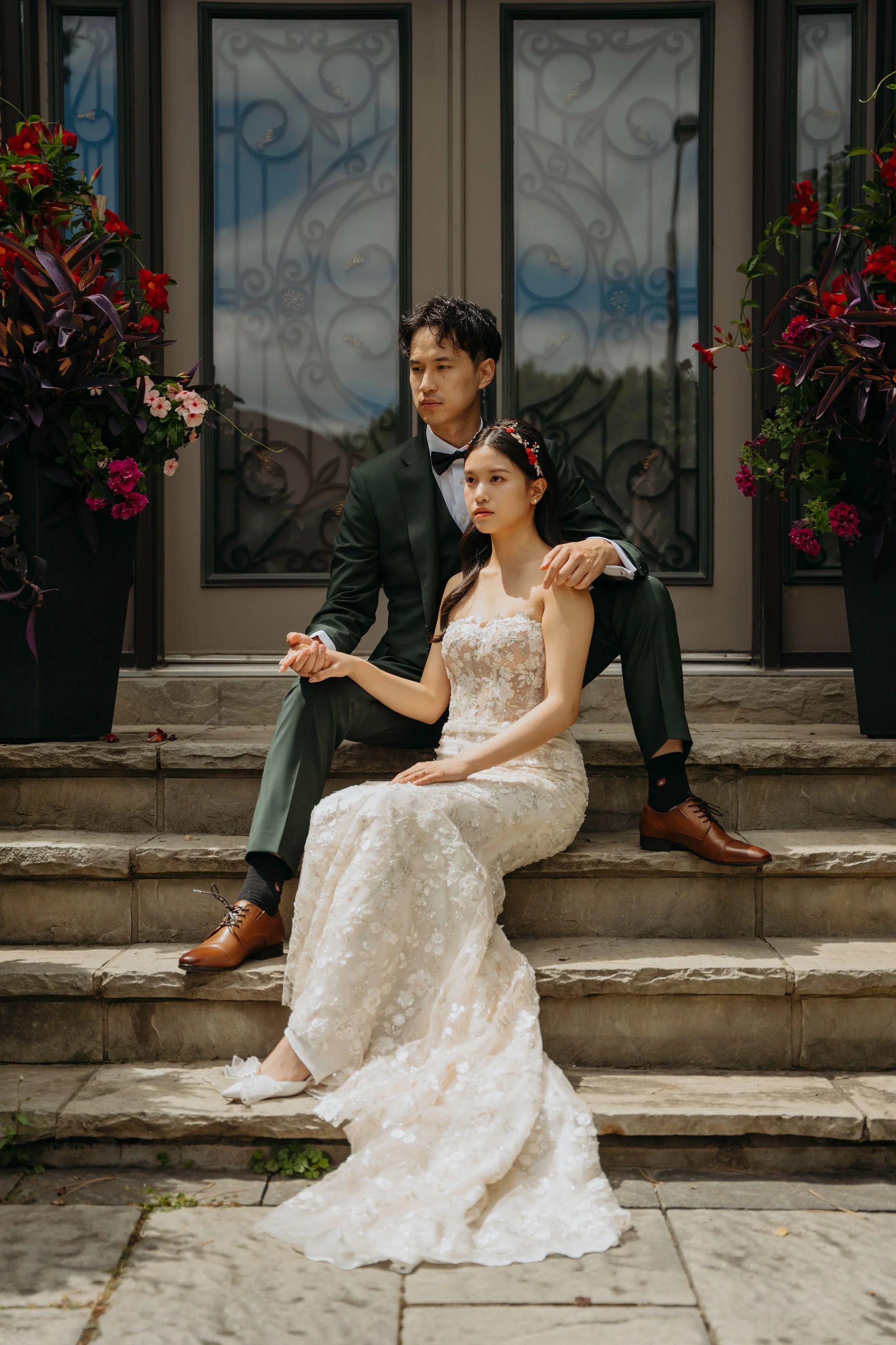 Bride and Groom posing on front steps of family home looking stoic