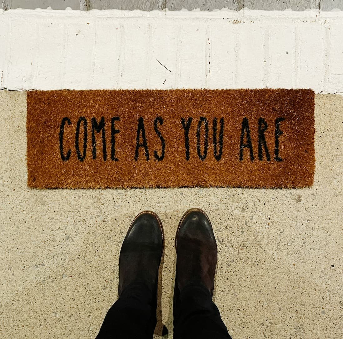 Come As You Are doormat with a person standing in front of it