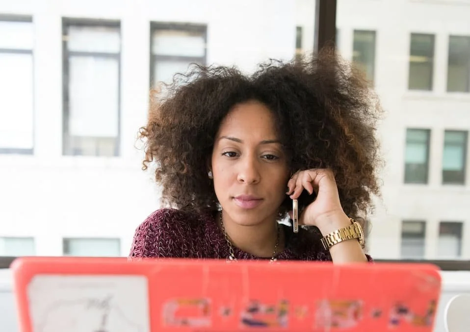 Professional woman working at a laptop while managing a phone call, illustrating high-functioning anxiety and workplace stress.