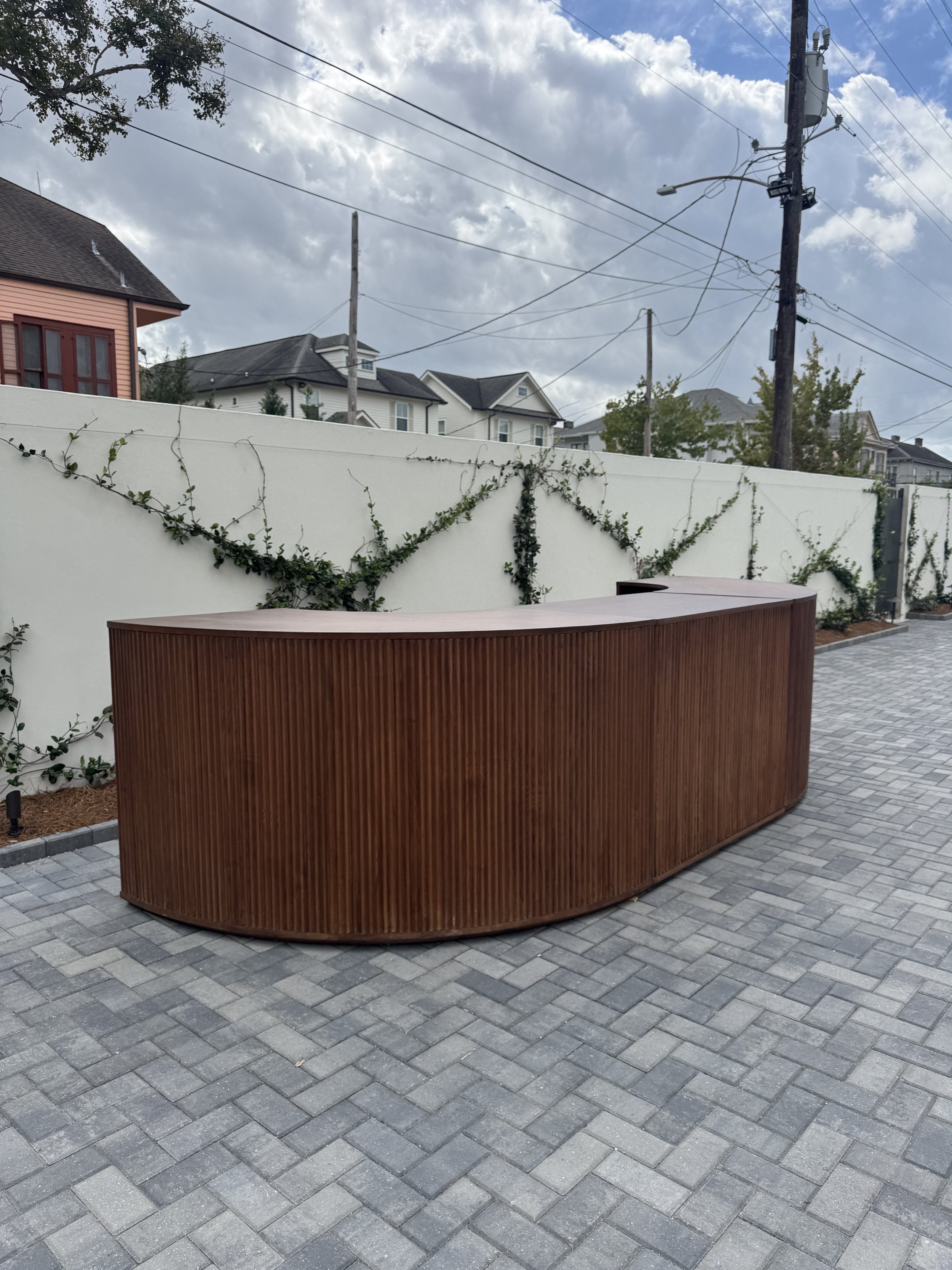 A courtyard wedding reception with a large walnut wood bar at the Josephine in New Orleans.