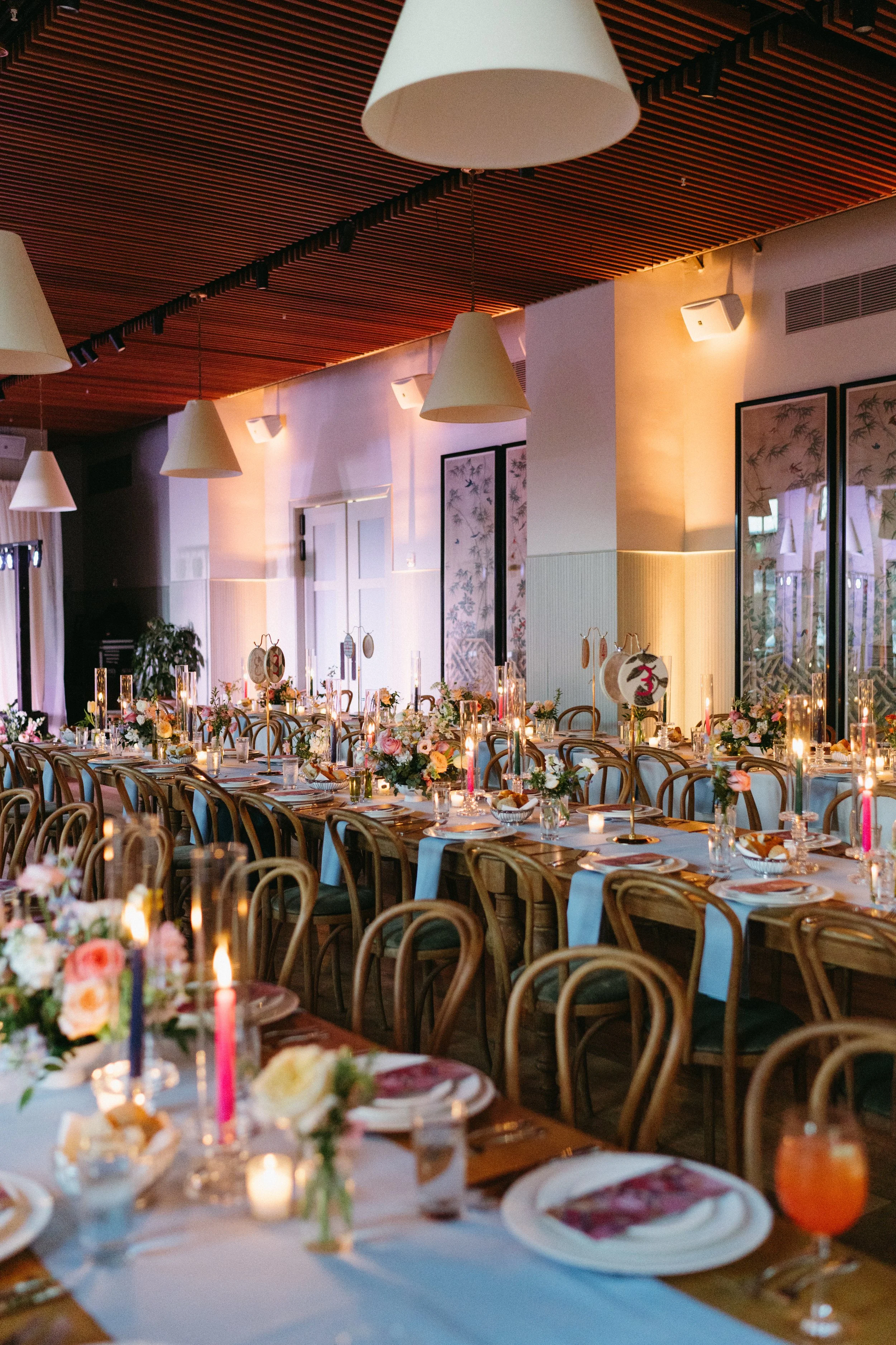 Wedding reception seated dinner with wooden tables and bentwood chairs at Hotel Saint Vincent in New Orleans.