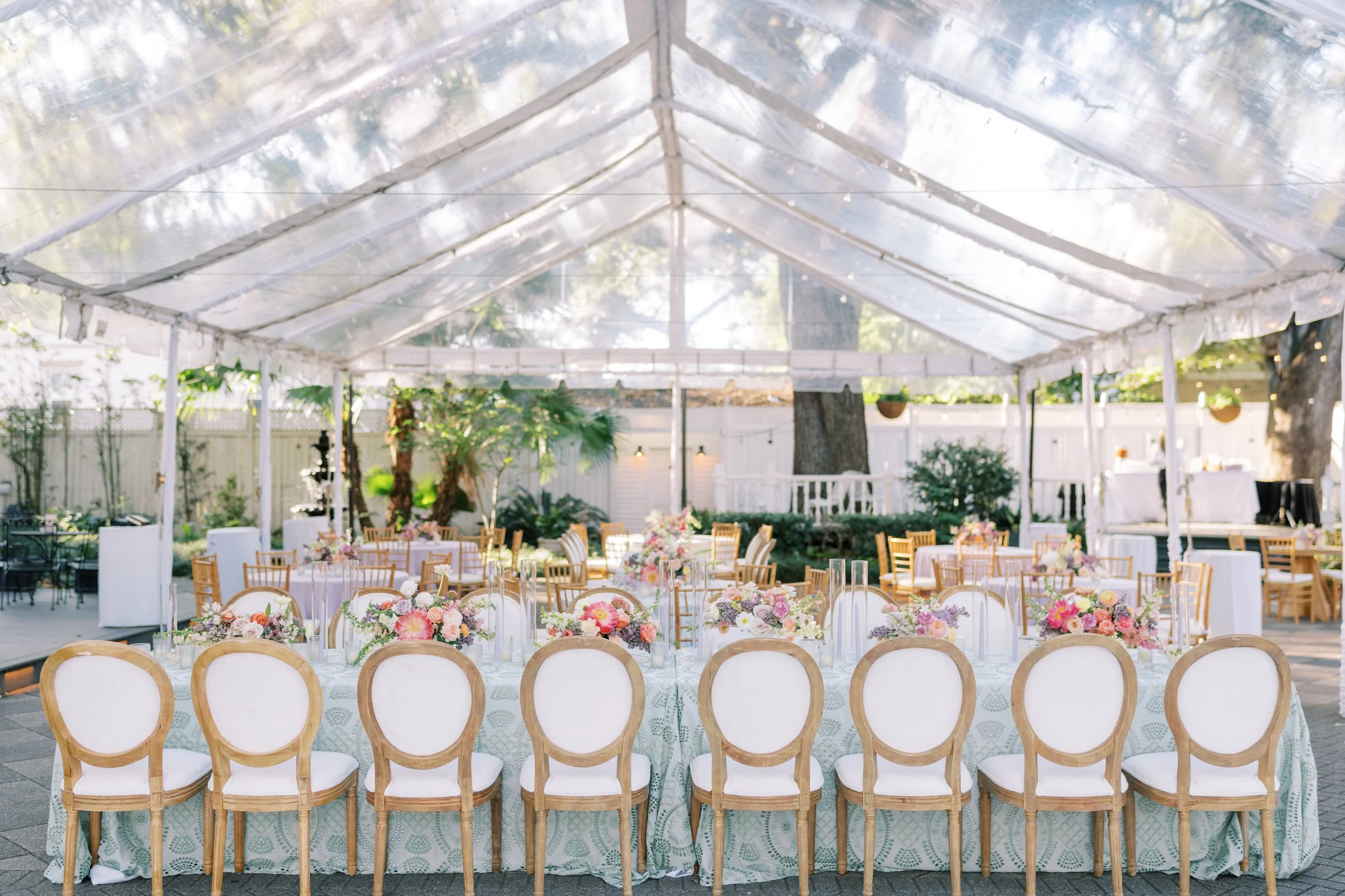 Wedding reception seated dinner with linen round back dining chairs and a wood dining tables at Elms Mansion in New Orleans. 