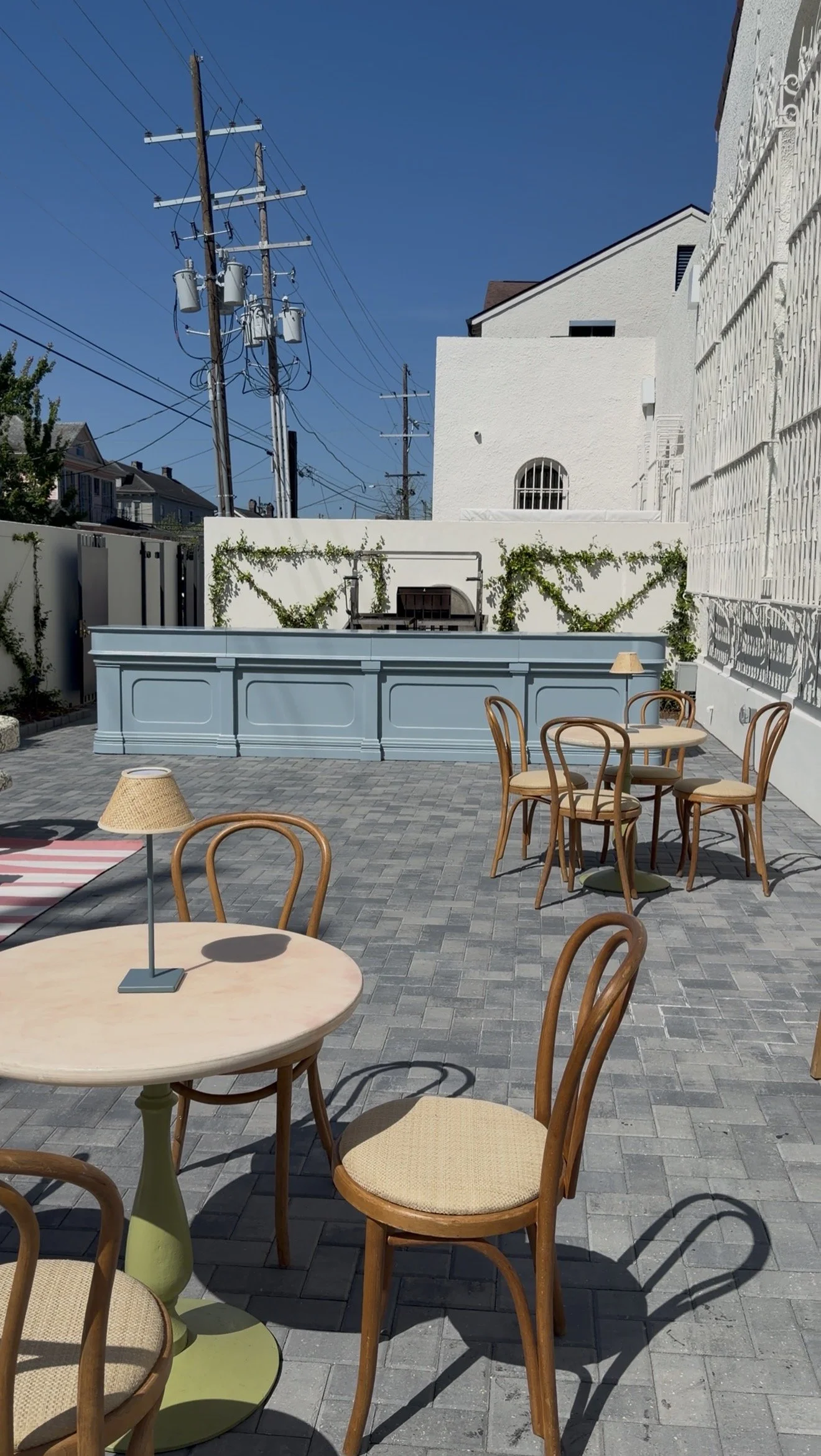 A courtyard wedding reception with a large blue bar and cabaret seating with wood dining chairs at the Josephine in New Orleans.