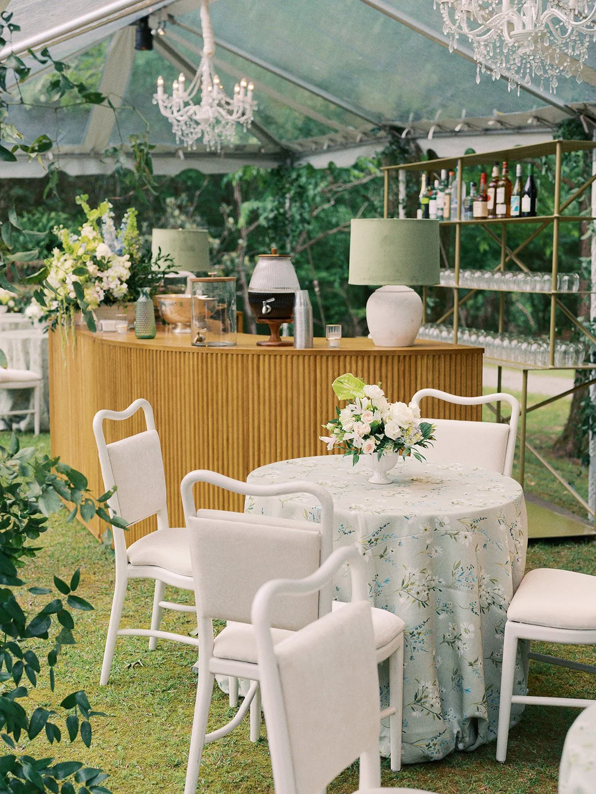 Luxury wedding reception design with white cushion dining chairs and large oak wood bar with lighting at Field and Forest in Mississippi. 