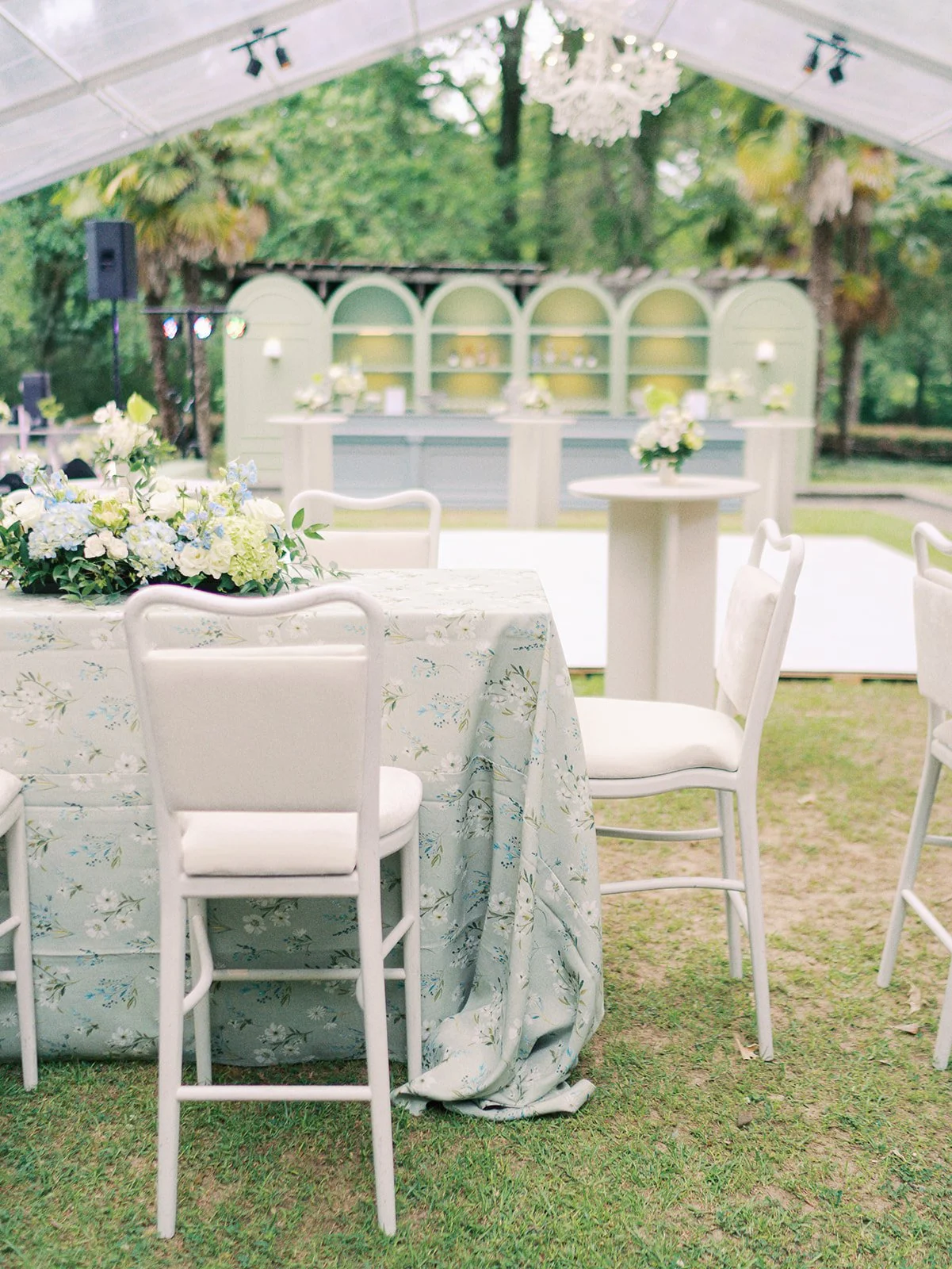 Luxury wedding reception design with white cushion barstools, large blue bar with pistachio barbacks and lighting at Field and Forest in Mississippi. 