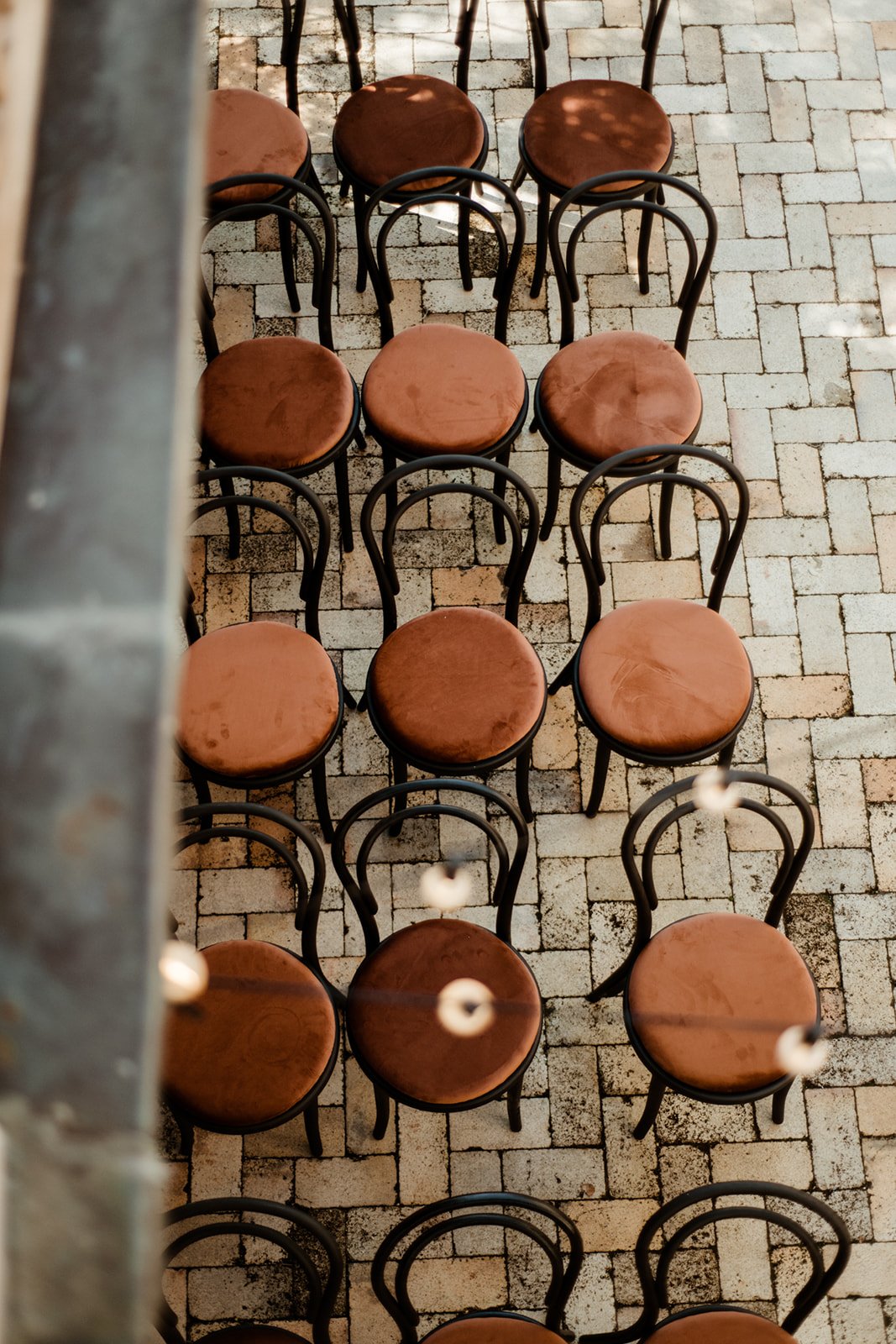 Rows of empty brown-cushioned chairs with black frames arranged on a tiled floor, viewed from above.
