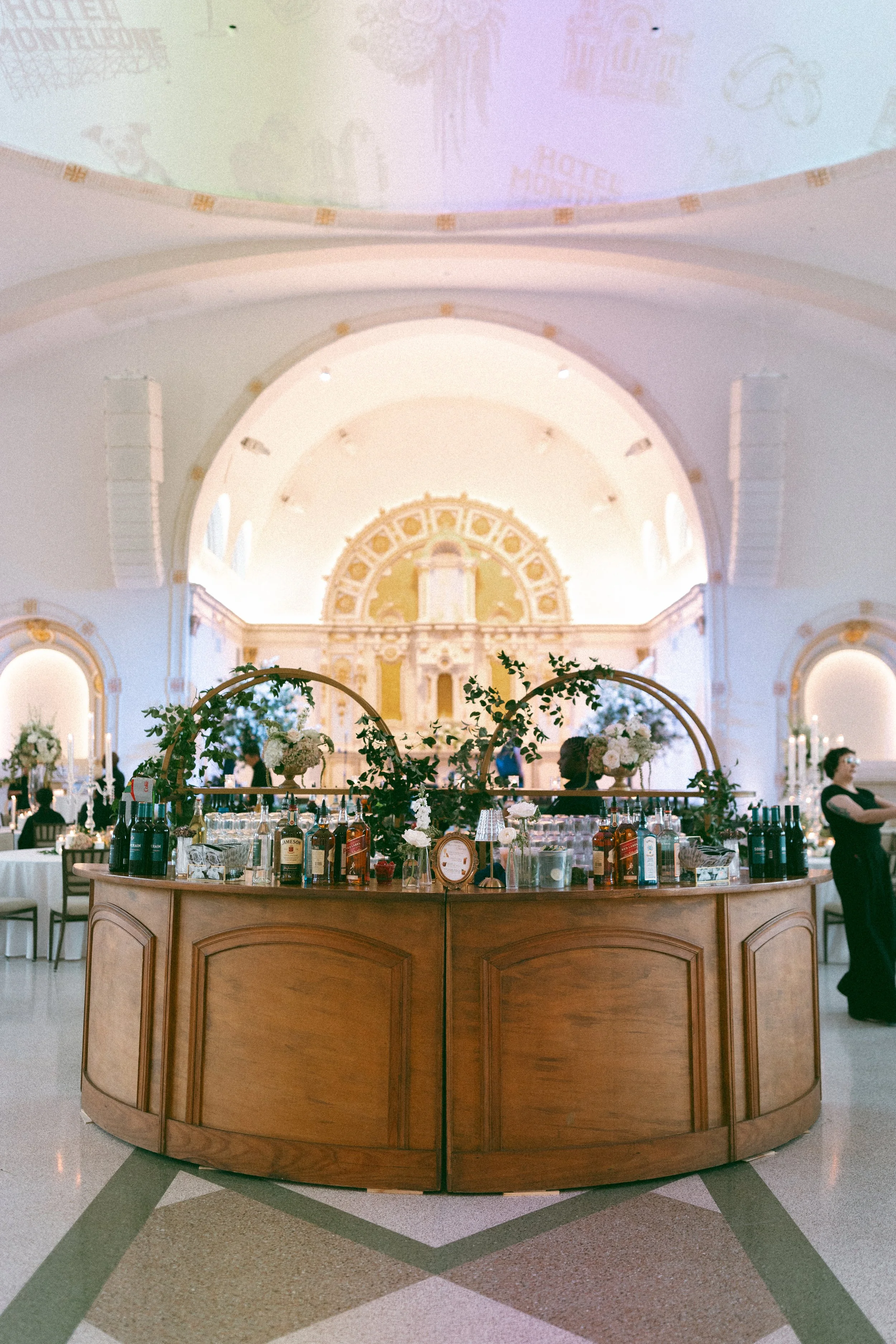 A wedding reception with a Natural wood round bar and gold barbacks at the Josephine in New Orleans.