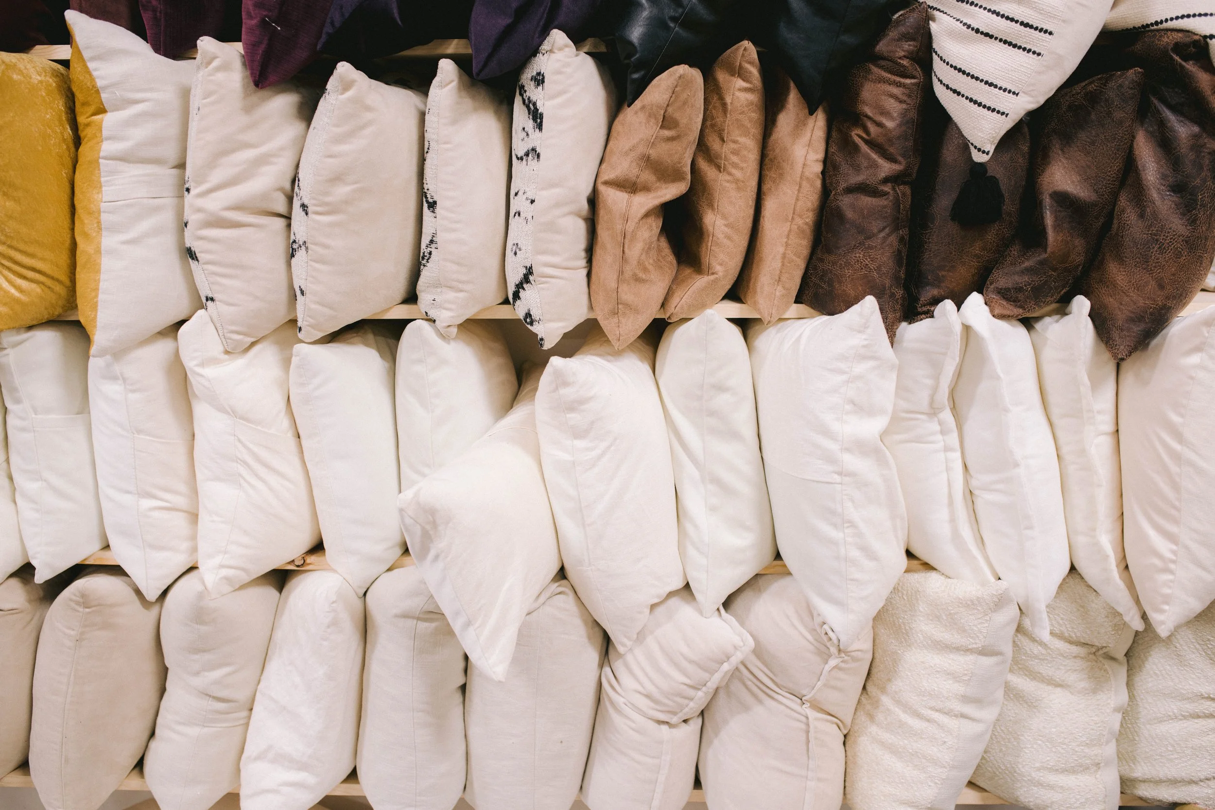A display of various pillows arranged neatly in rows, featuring different colors, textures, and patterns.