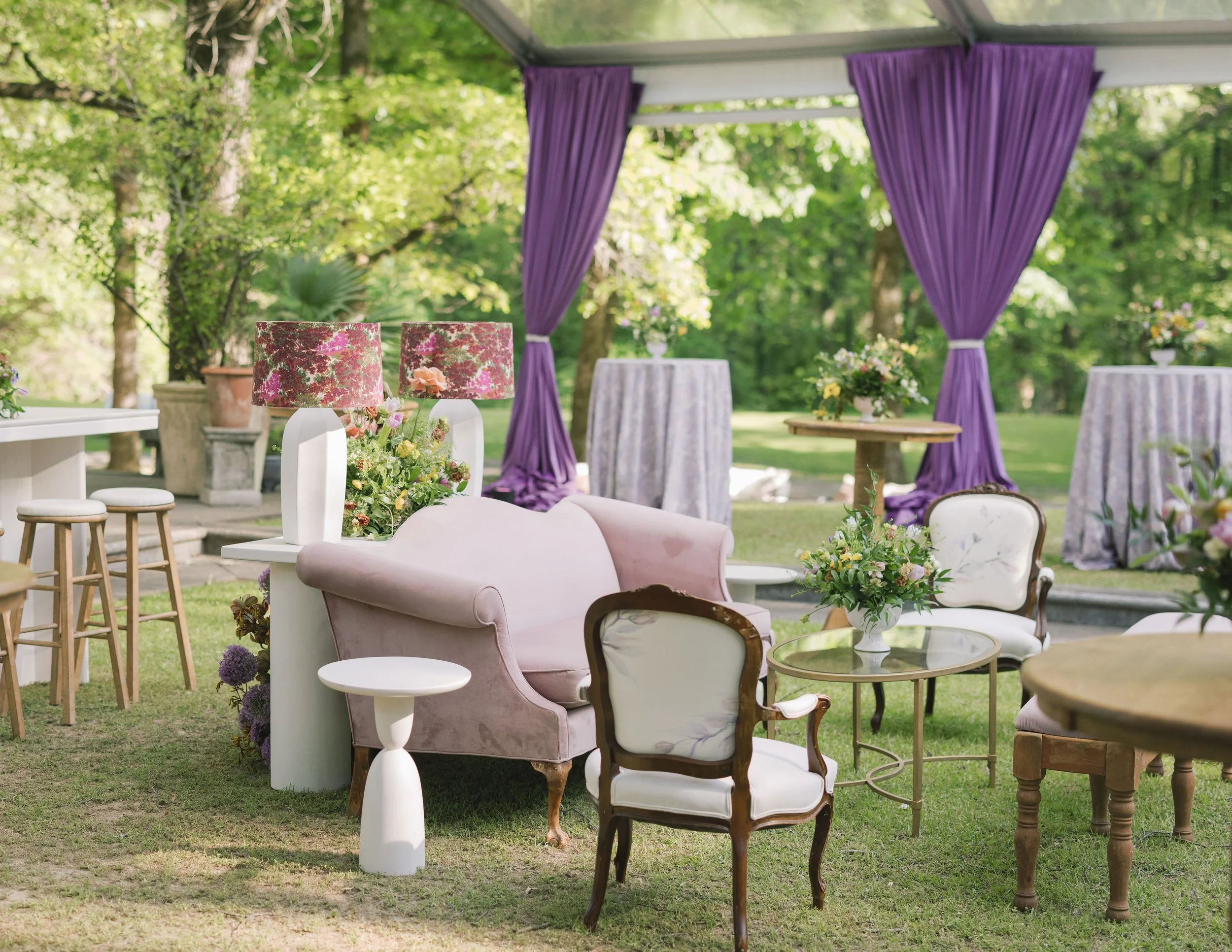 Luxury wedding reception design with vintage purple sofa and vintage white chairs with a white console tables and pink floral lamps at Field and Forest in Mississippi. 