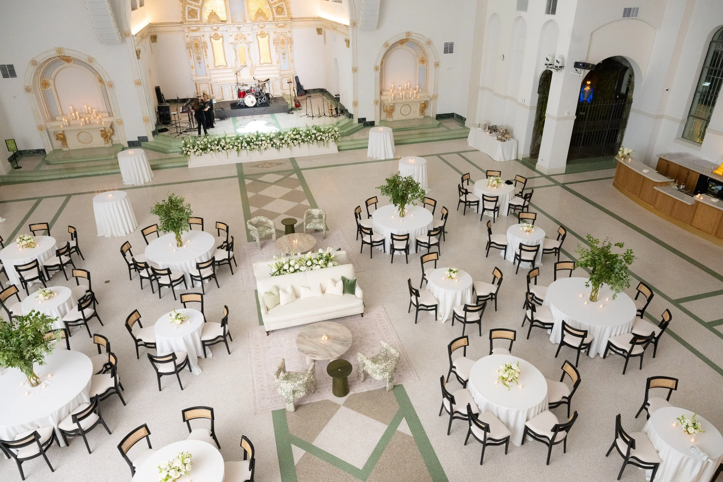 A wedding reception with black dining chairs and cream cushions. Also a double white and green lounge area at the Josephine in New Orleans.