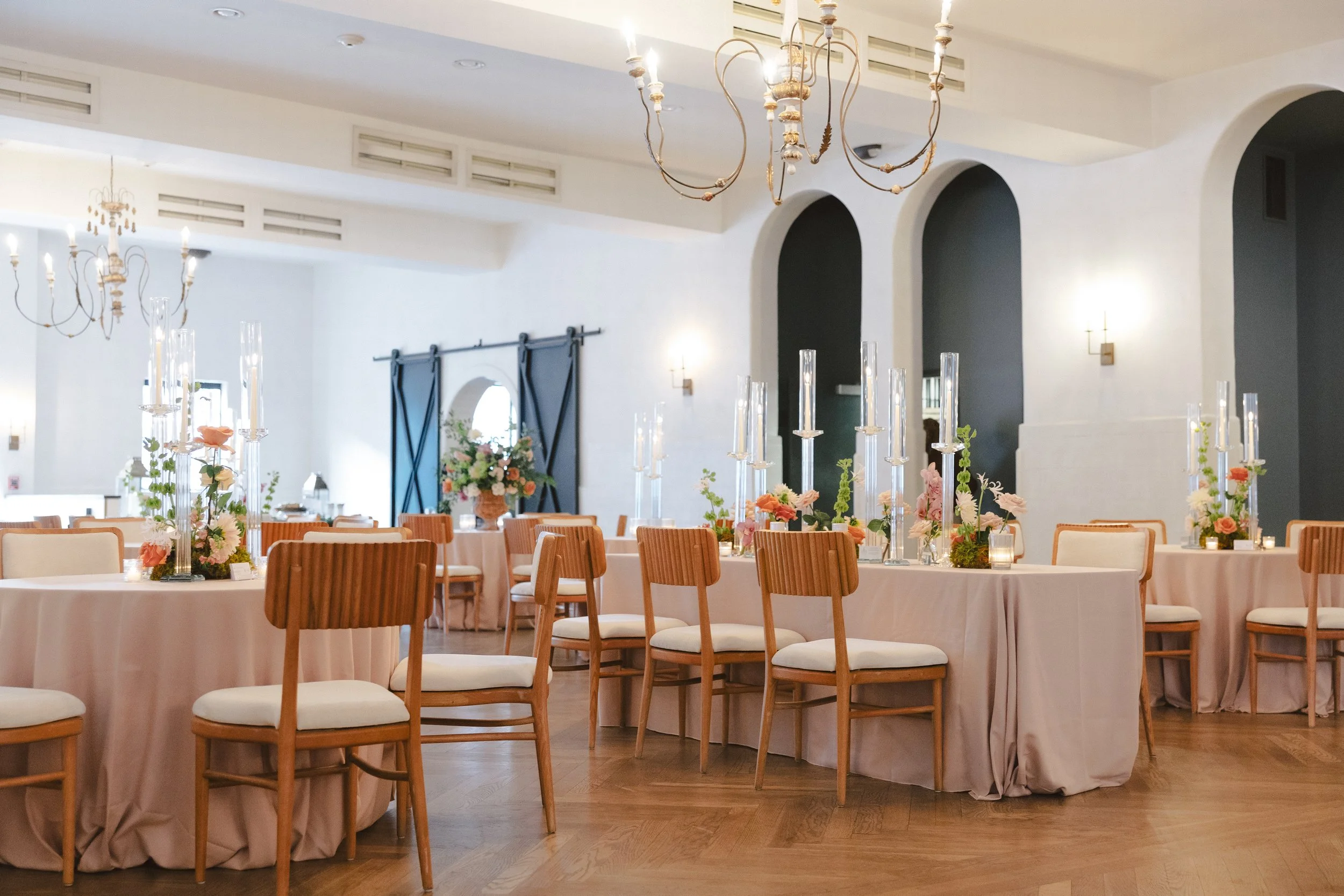 A seated wedding reception with oak wood dining chairs and tables at Il Mercato in New Orleans.