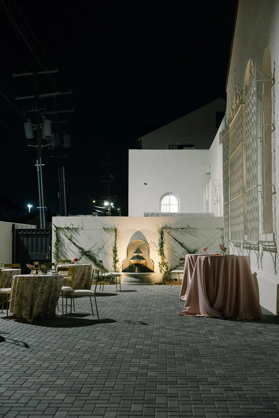 A courtyard nighttime wedding reception with gold dining chairs and round tables at the Josephine in New Orleans.