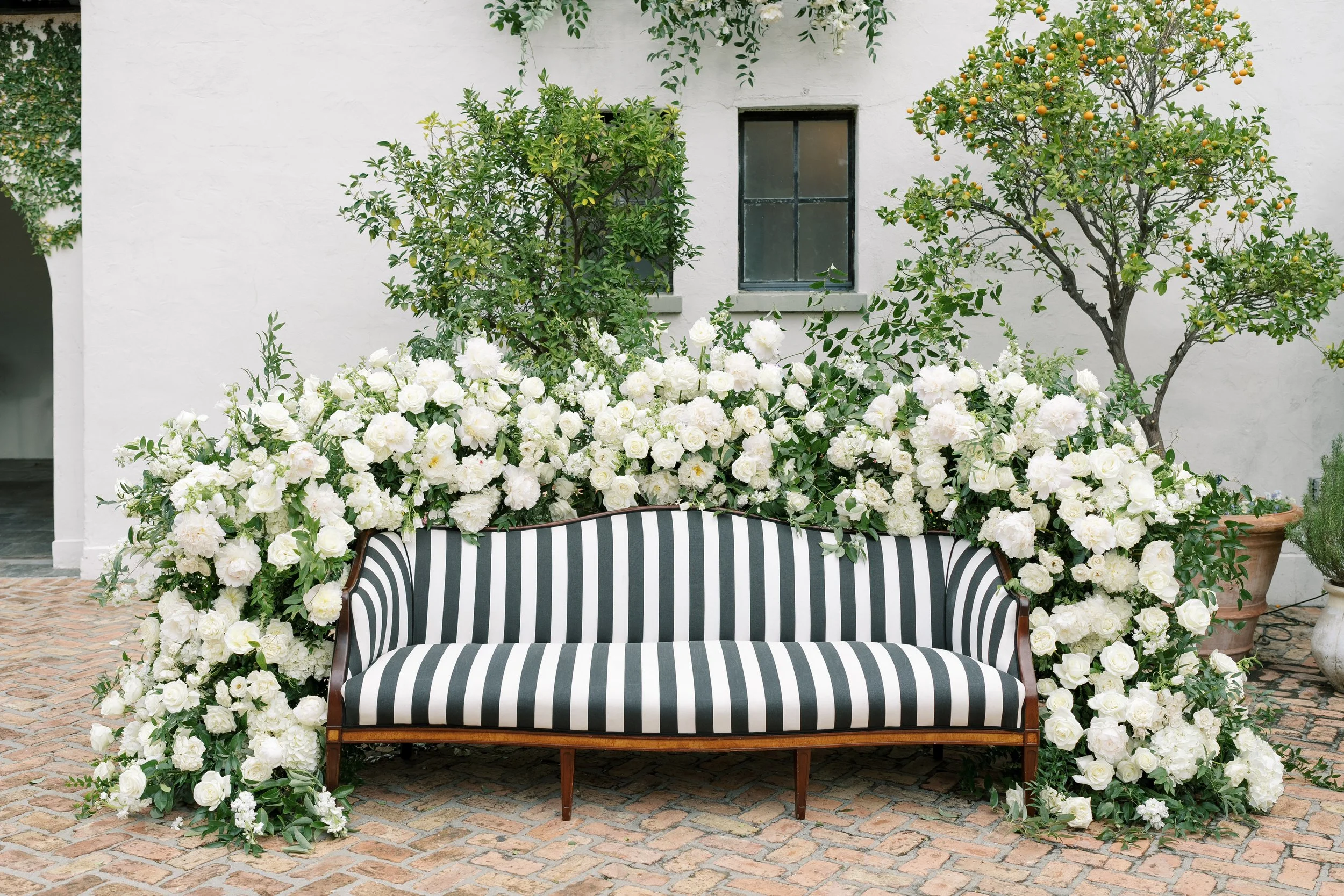  A wedding photo booth area with a black and white stripe sofa and florals framing the sofa at Il Mercato in New Orleans.