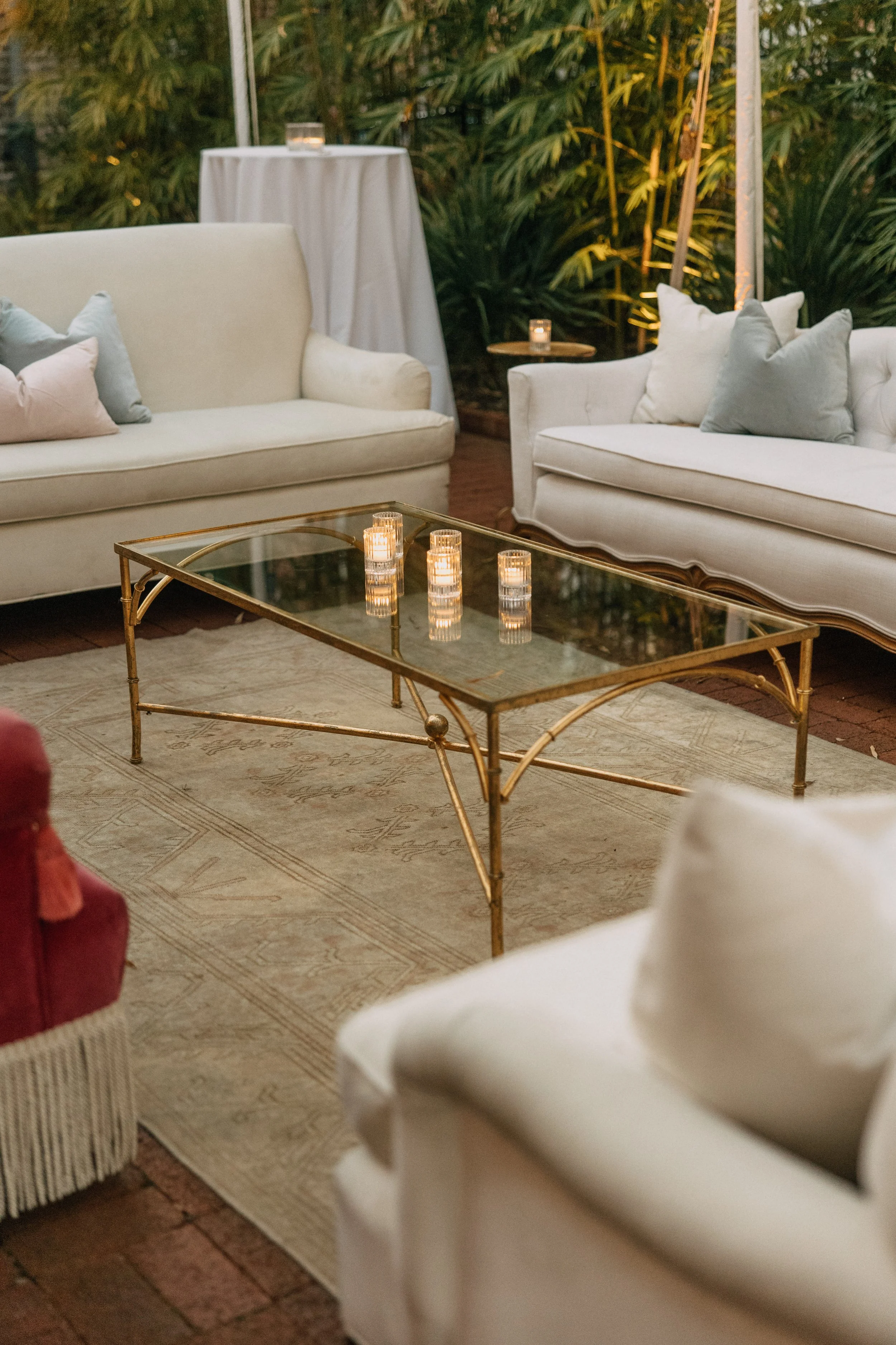 Outdoor wedding reception lounge design with a cream vintage lounge, pink chairs, and gold coffee tables at Hotel Saint Vincent in New Orleans.