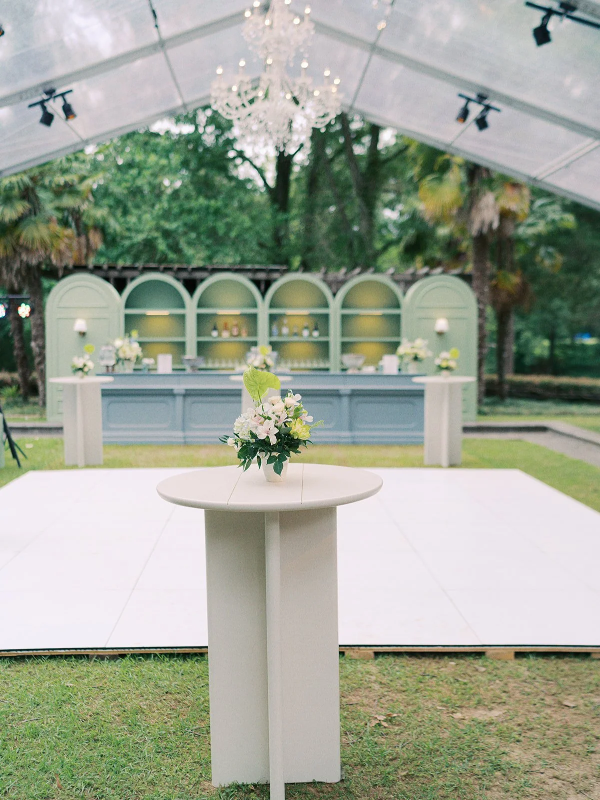Luxury wedding reception design with white cushion barstools, large blue bar with pistachio barbacks and lighting at Field and Forest in Mississippi. 