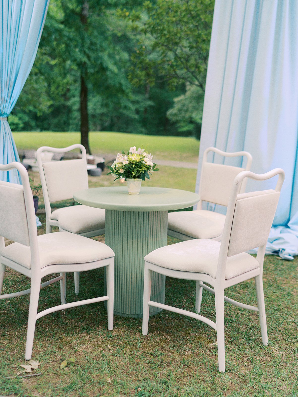 Luxury wedding reception design with pistachio green cabaret table and white dining cushions at Field and Forest in Mississippi. 
