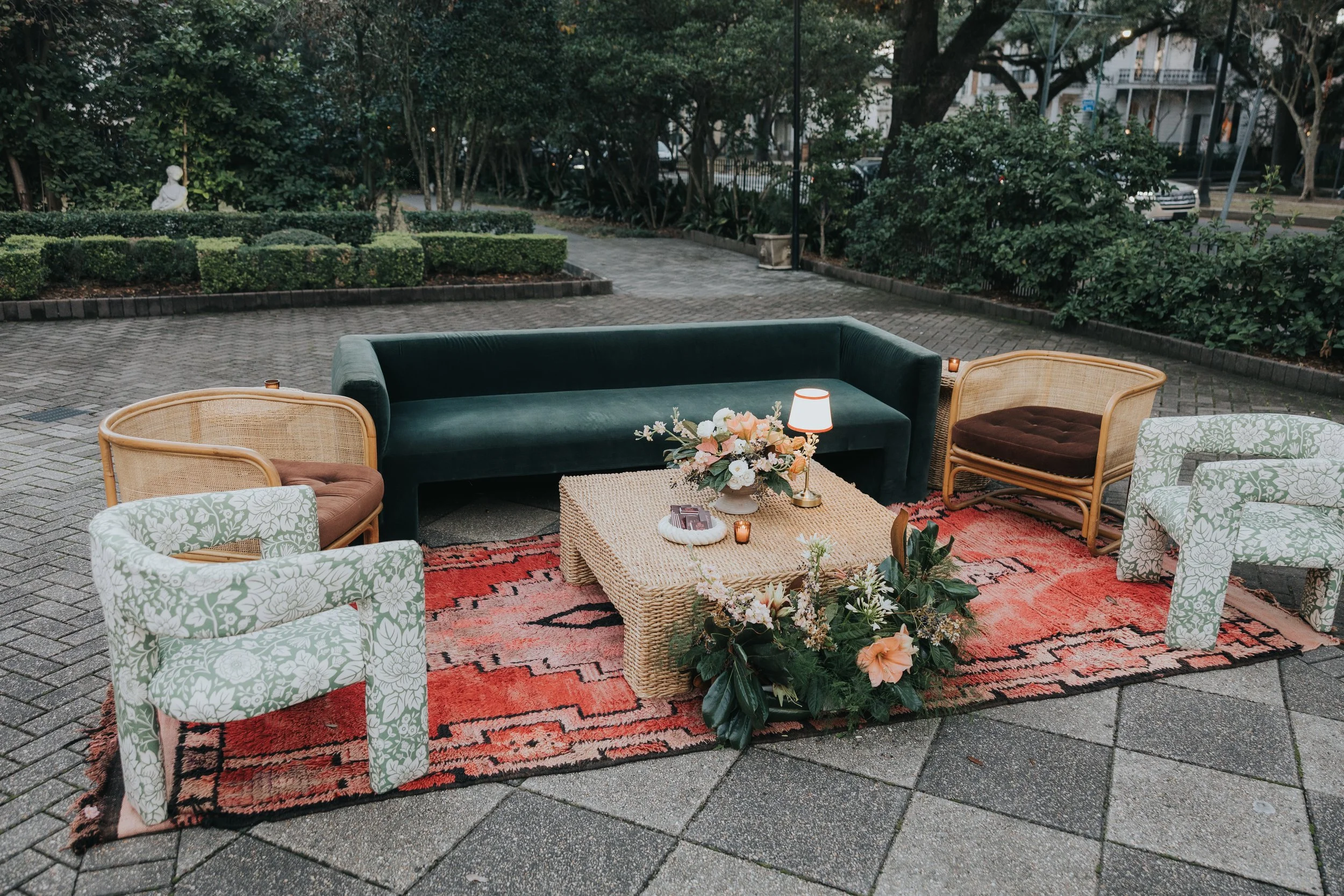 Wedding reception lounge design with green sofa, green floral chairs, rattan coffee table and rug tribal rug at Elms Mansion in New Orleans. 