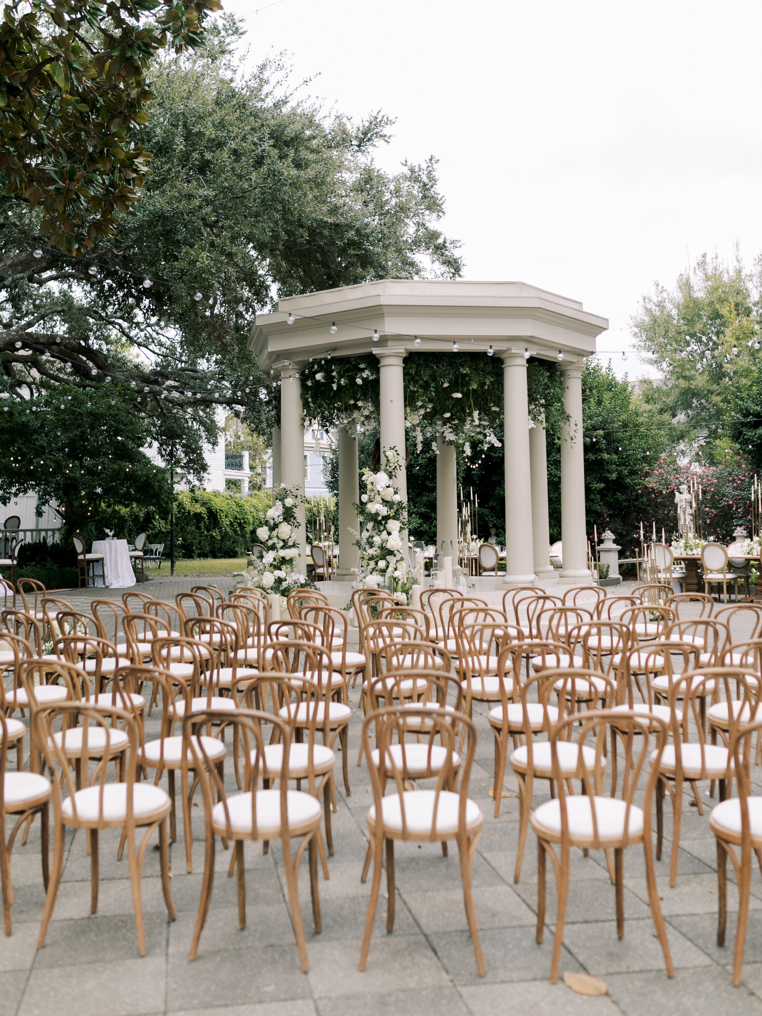 Outdoor wedding ceremony with natural wood dining chairs at the Elms Mansion in New Orleans. 