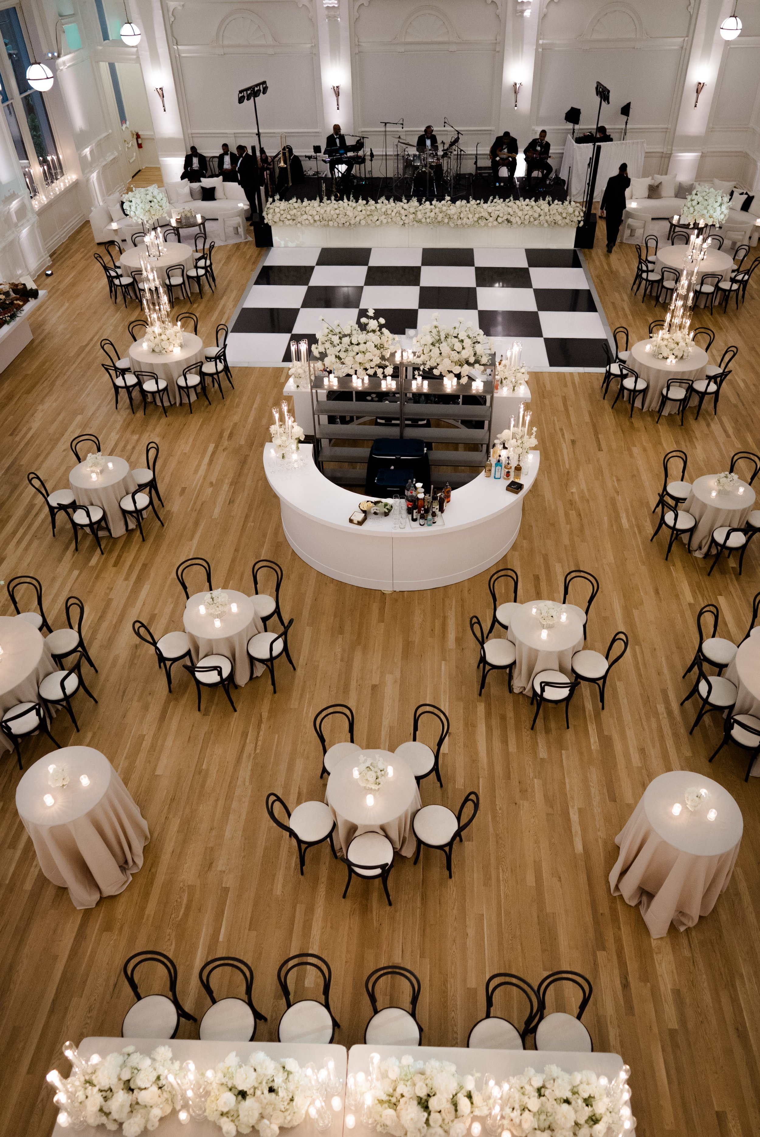 Wedding reception design with a large white round bar, tables set with black dining chairs at the New Orleans Board of Trade.