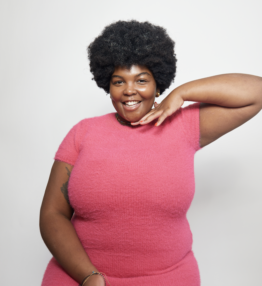 Kira Matthews, woman with Afro smiling in pink dress