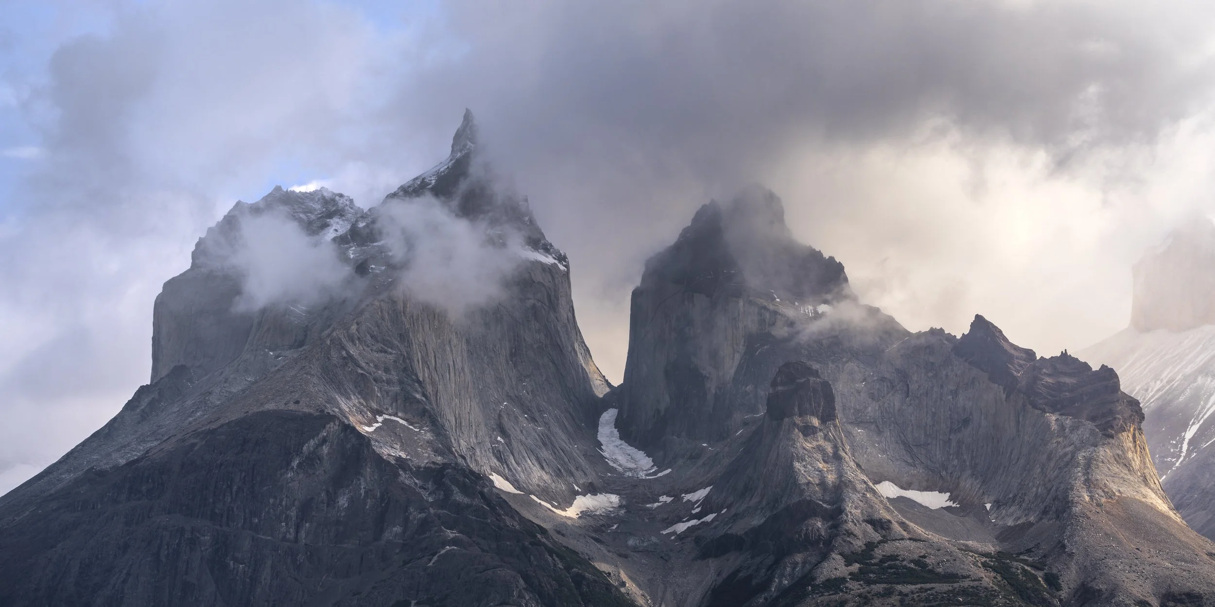A view of only the rocky peaks of Torres Del Pain surrounded by clouds lit up by the morning sun