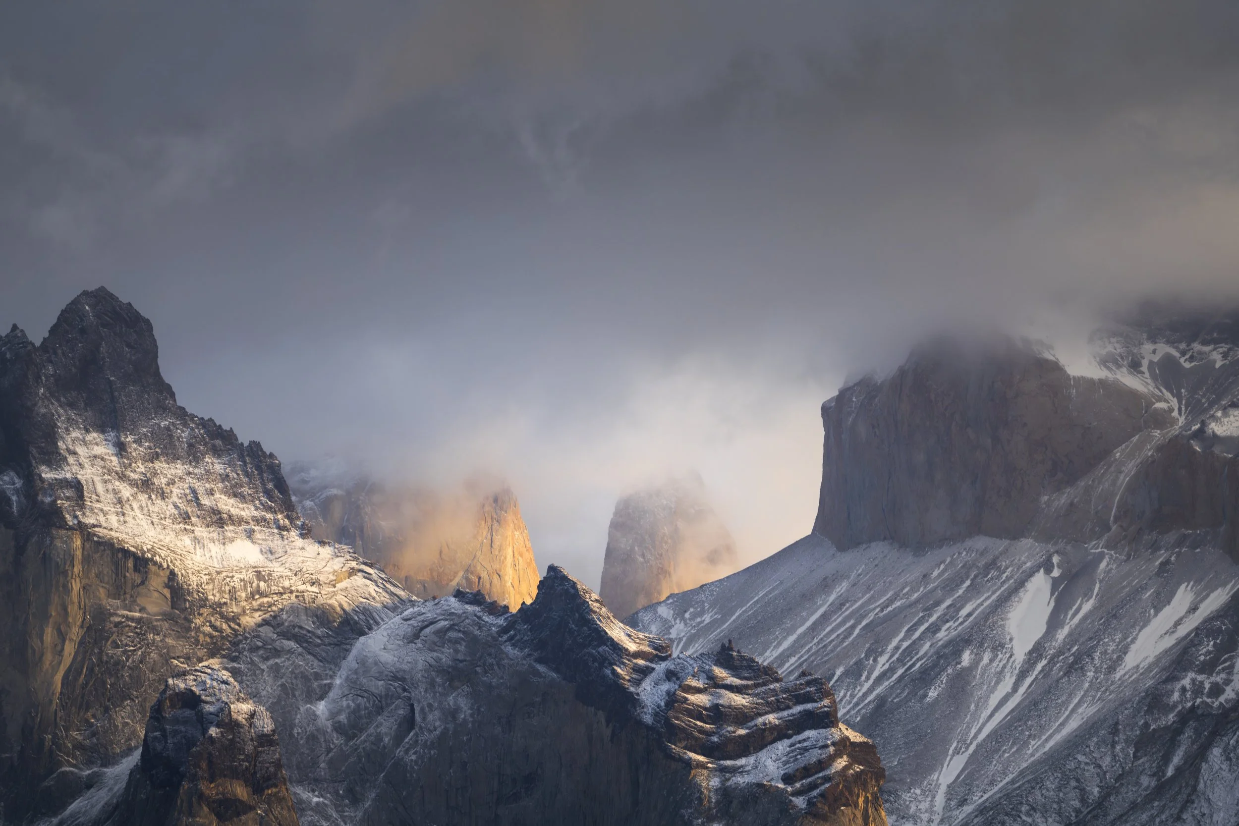 Layers of clouds passing around the rocky peaks of torres del pain. The rocks in the middle being lit up by the morning sun