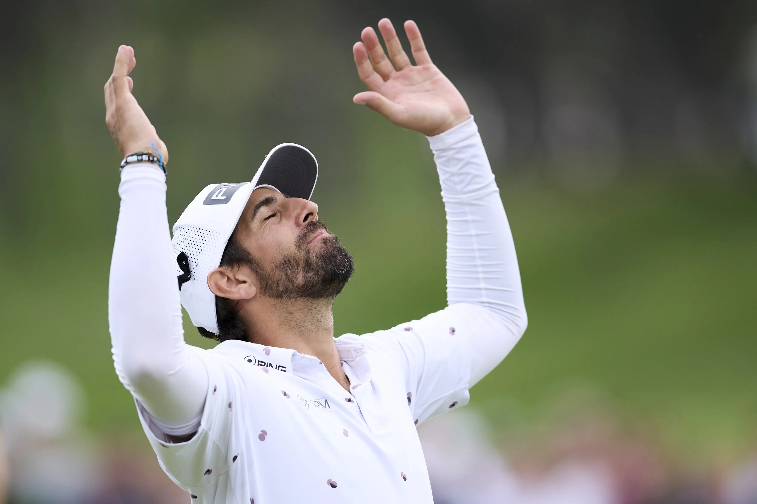 Jugador de golf levantando los brazos en señal de victoria con ojos cerrados y expresión de emoción en un campo de golf