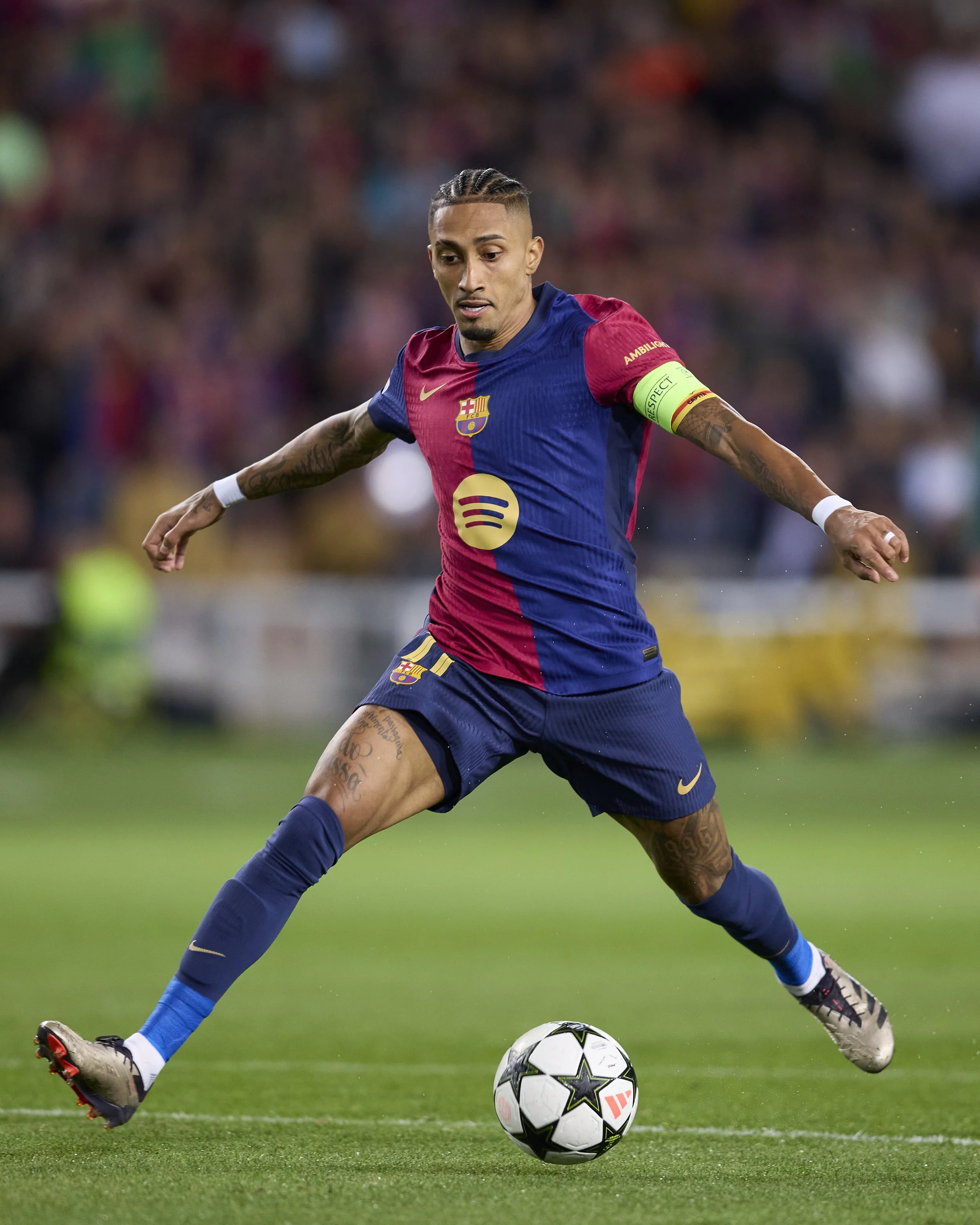 Jugador de fútbol de Barcelona en acción en el campo, vestido con uniforme azul y rojo, con balón en juego.