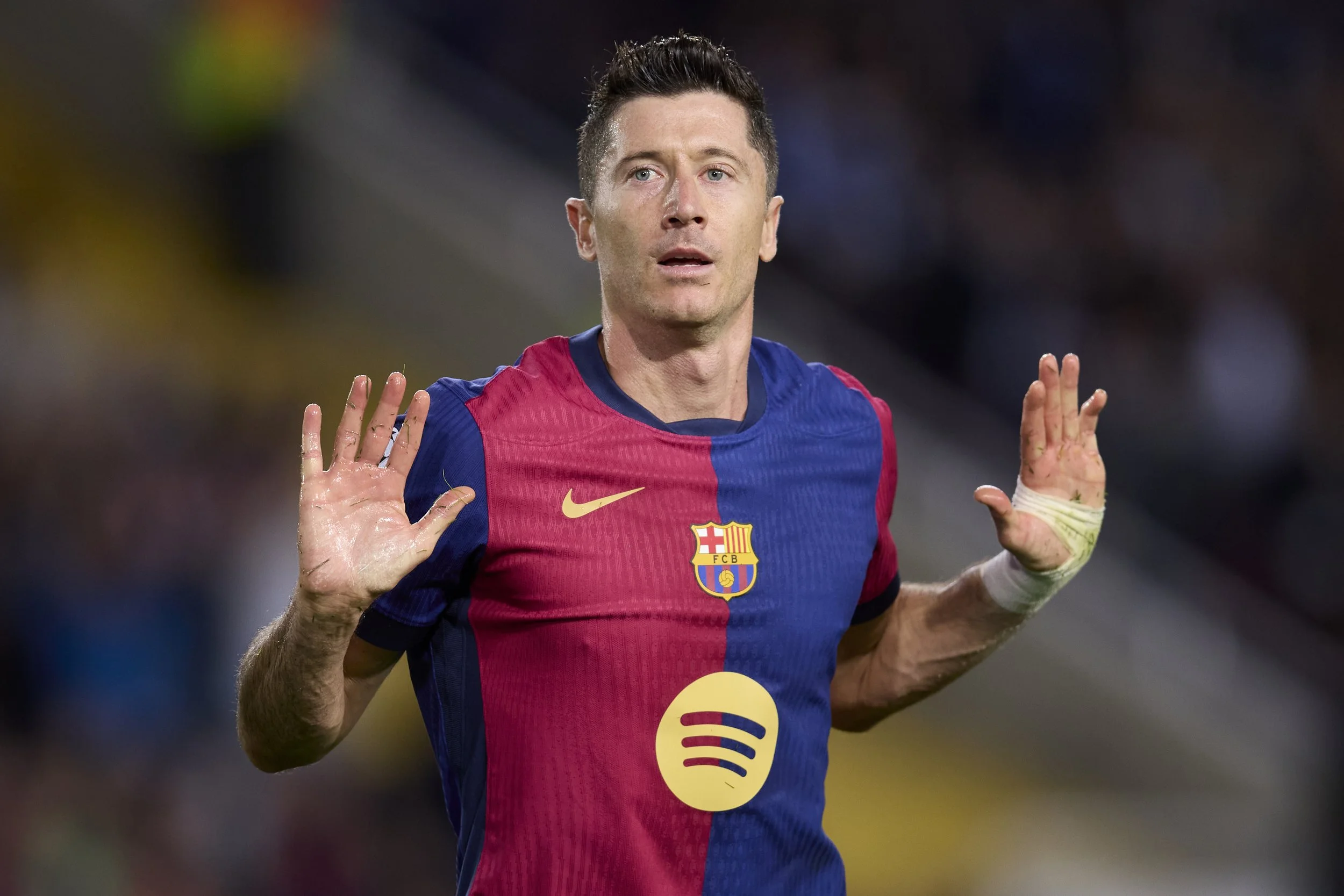 Jugador de fútbol con camiseta del FC Barcelona, levantando las manos, en un partido.
