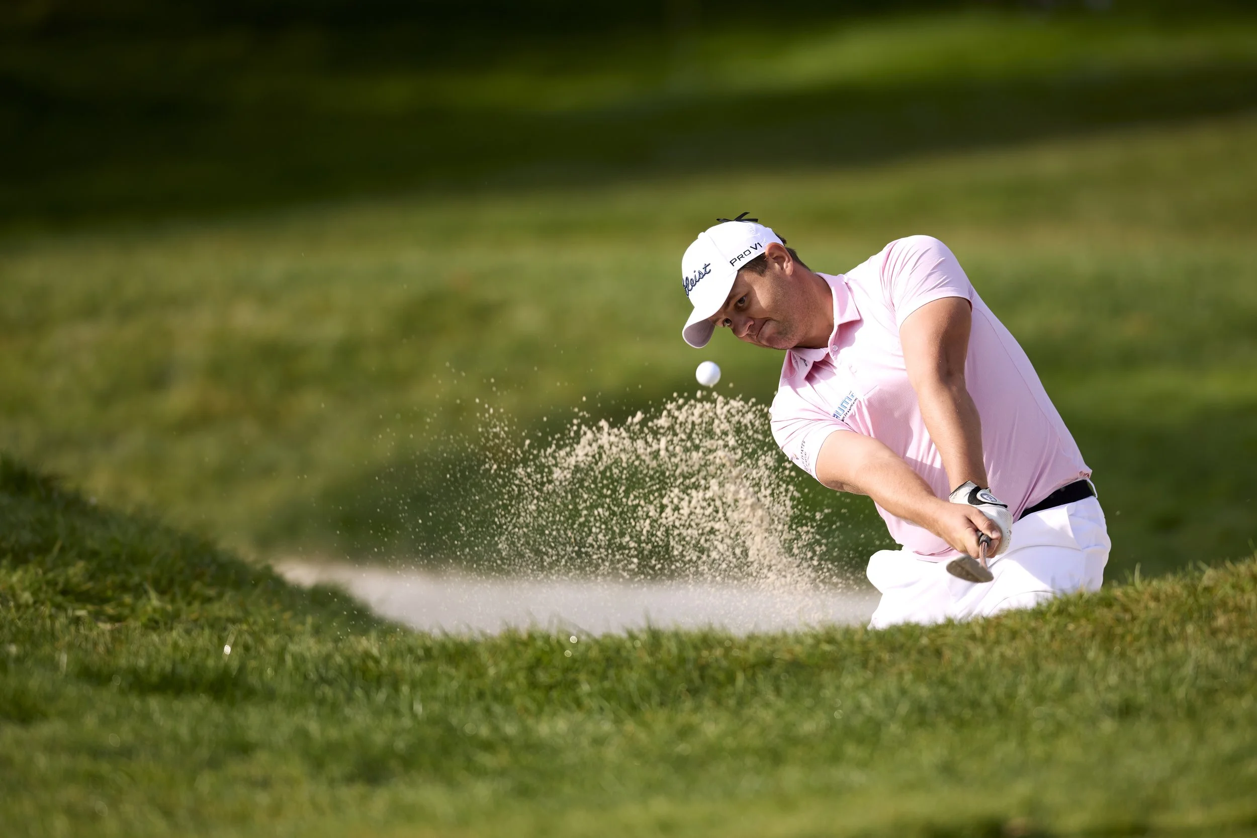 Golfista en un bunker haciendo un golpe para sacar la pelota.