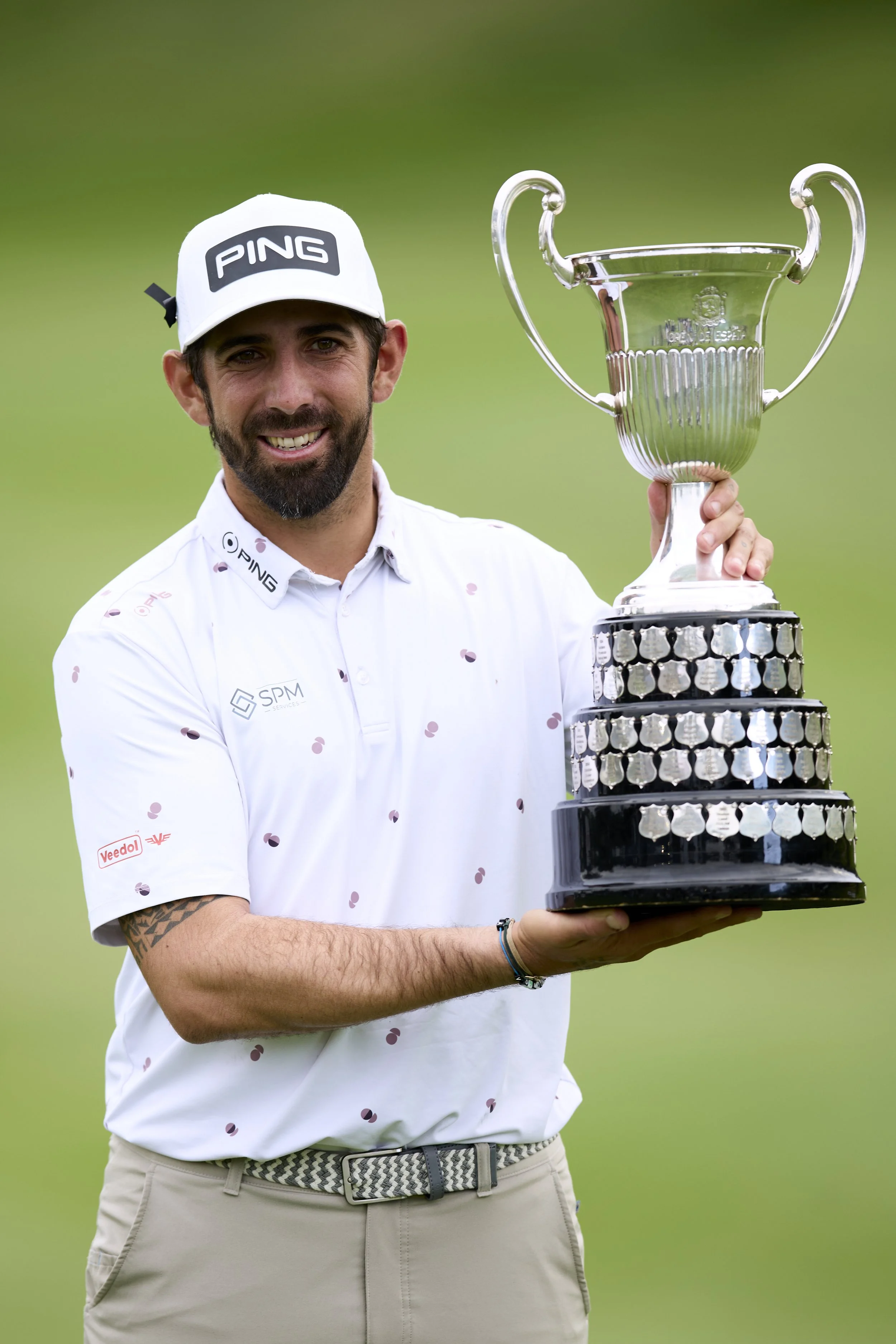 Un hombre sostiene un trofeo de golf con un fondo de césped verde.