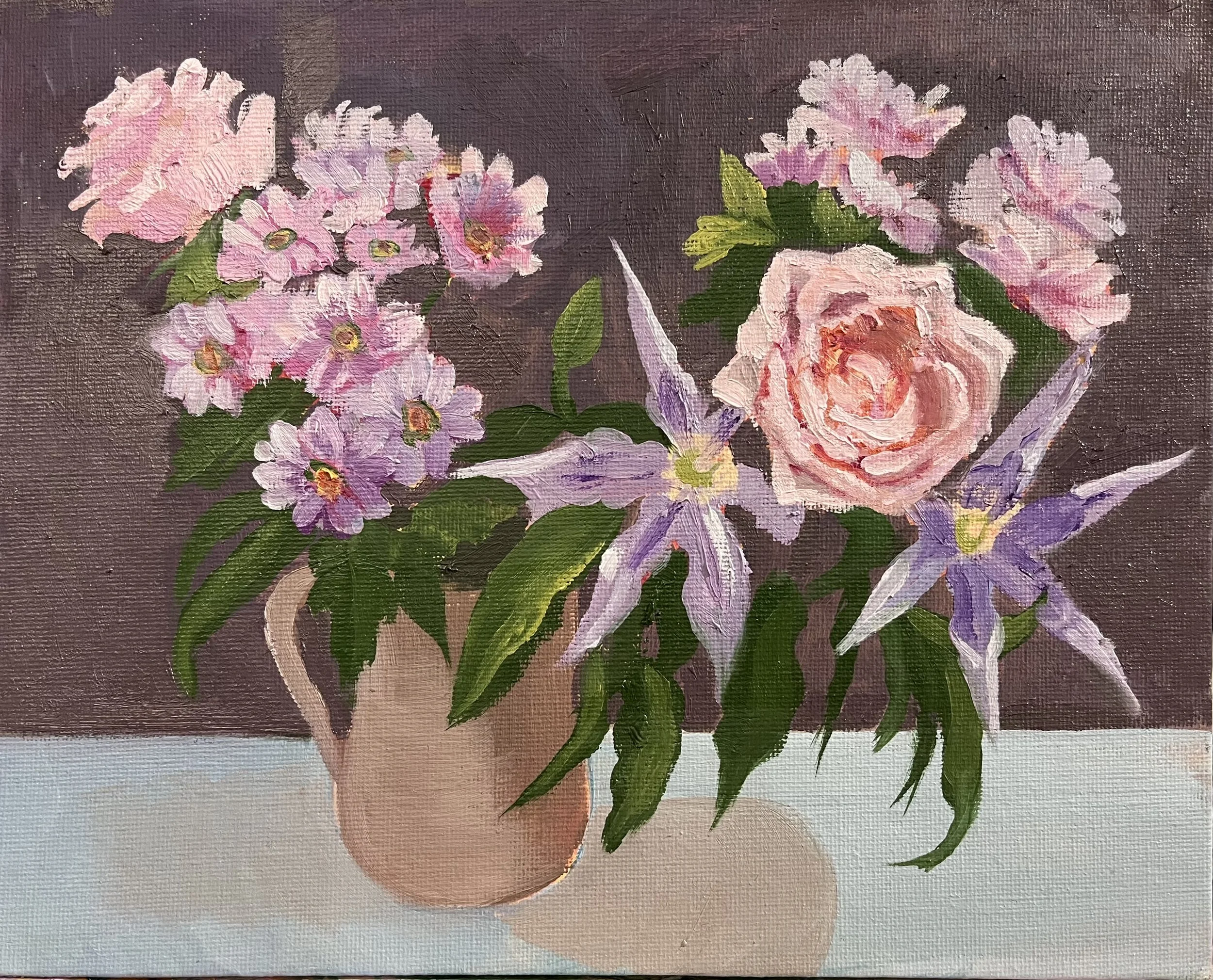The image shows a jug of lowers, two roses two cyclamen and some pink daisies with a brown background and a turquoise foregroun