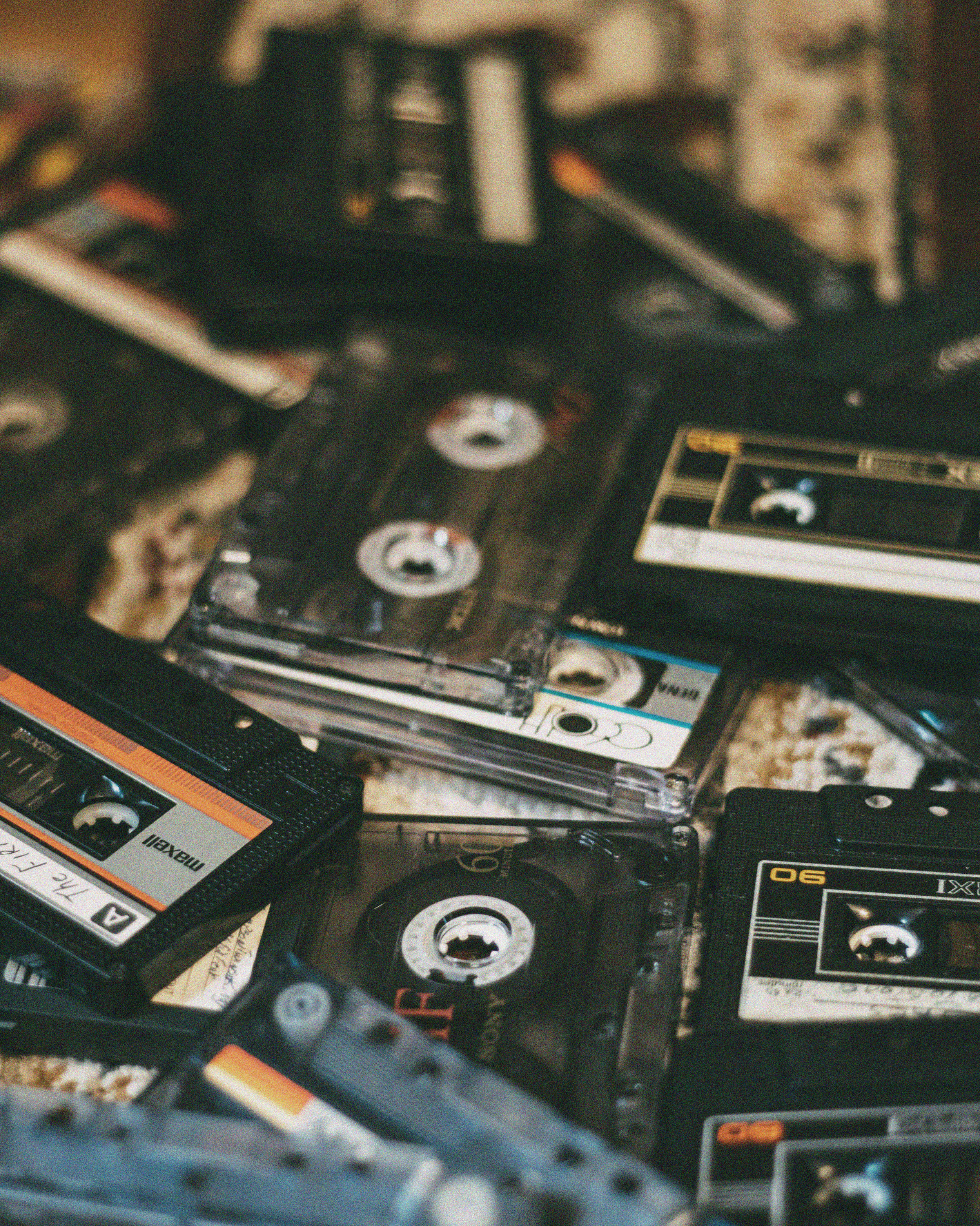 A pile of vintage cassette tapes with various designs and labels scattered on a patterned surface, evoking nostalgia and a retro vibe.