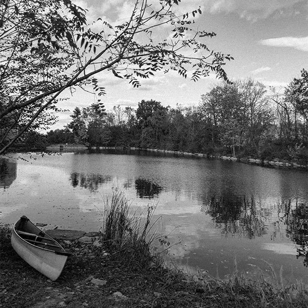Scenic view of a lake in a wooded are with a canoe on the shore