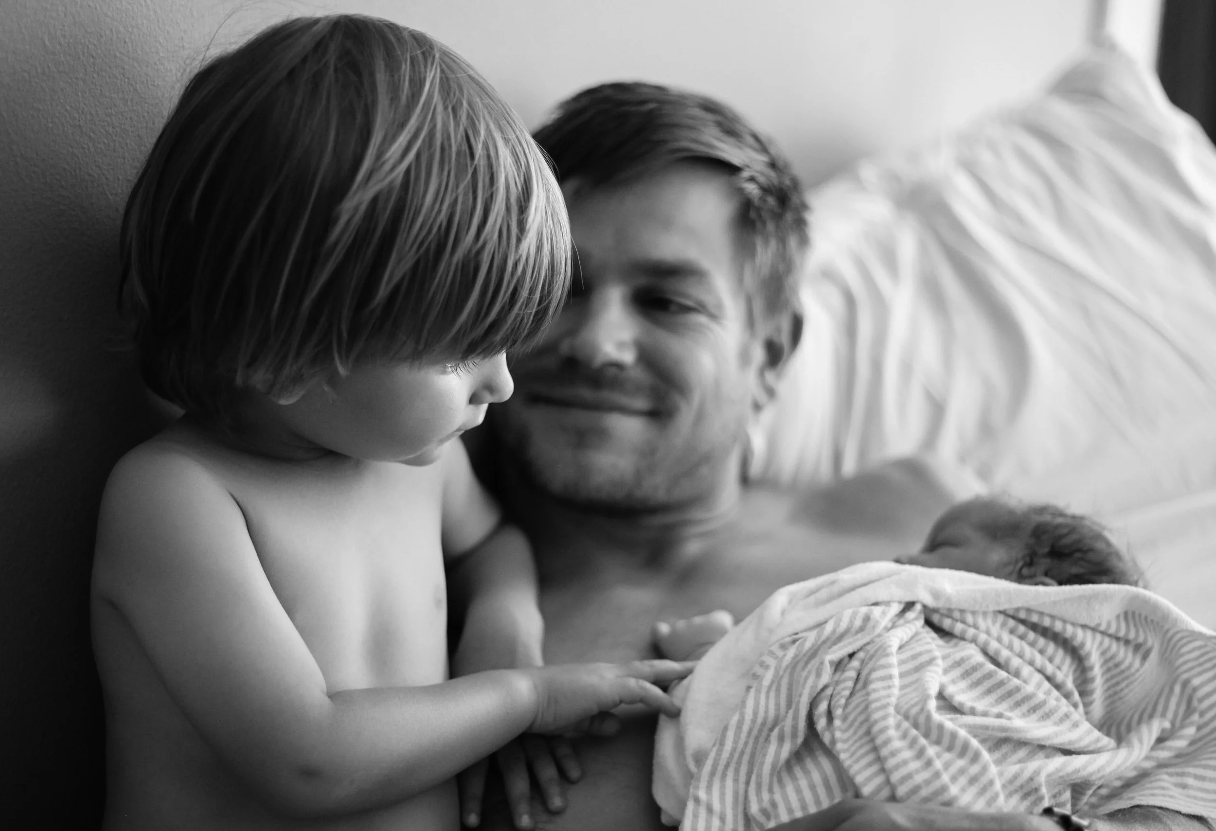 Dad and son admiring a newborn baby after a home birth in LA