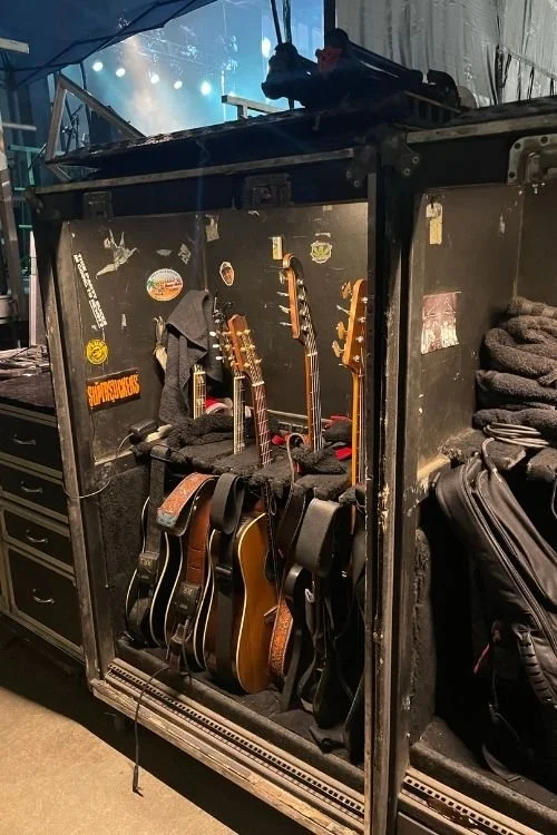 A storage container containing 5 acoustic guitars backastage at a concert