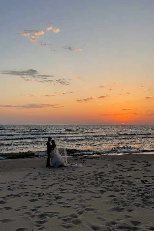 A bride and groom are dancing at their wedding reception inside a decorated tent, with guests watching in the background.