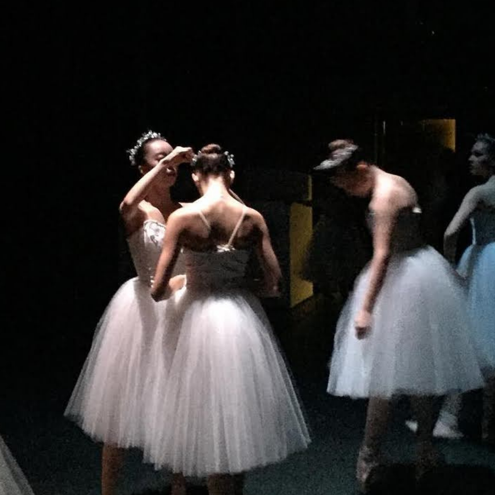 ballerinas touching each other up backstage